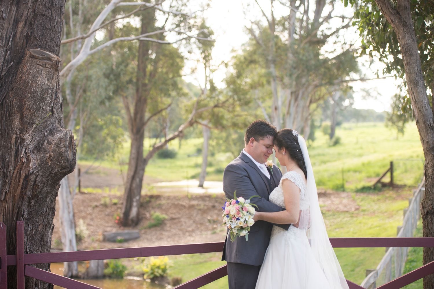 A romantic couple shares tender moments in a rustic outdoor setting during their wedding photoshoot.