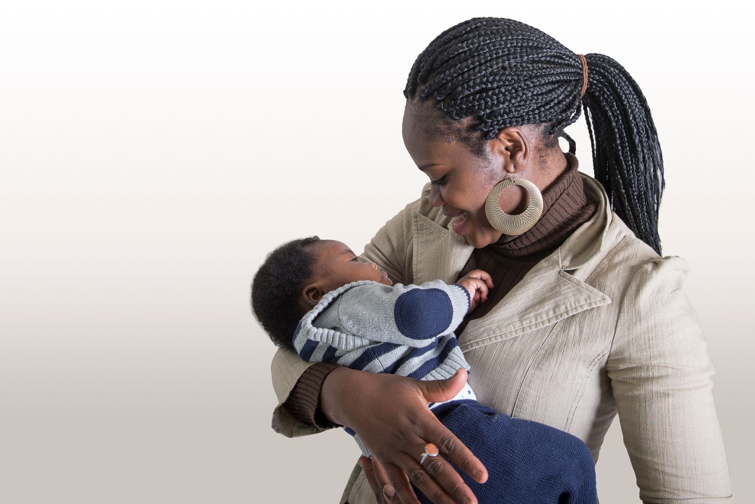 Parent holding newborn baby against white background in tender moment.