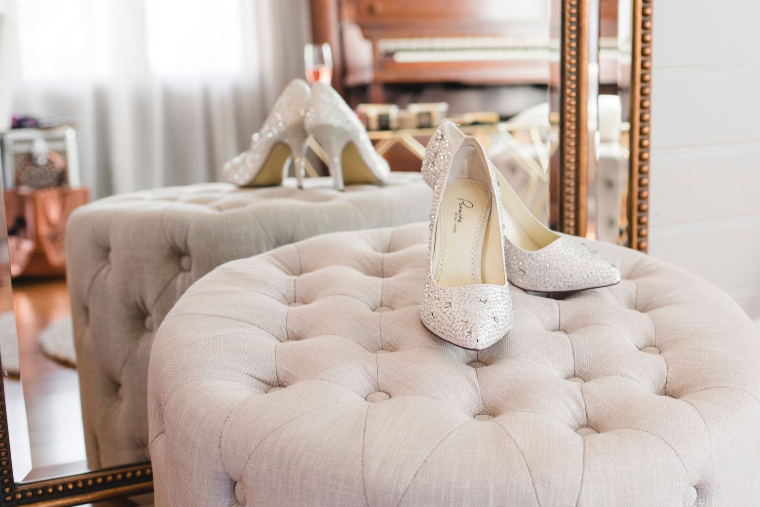 Elegant tufted beige velvet headboard with ornate gold mirror and white bedding in a luxurious bedroom setting.