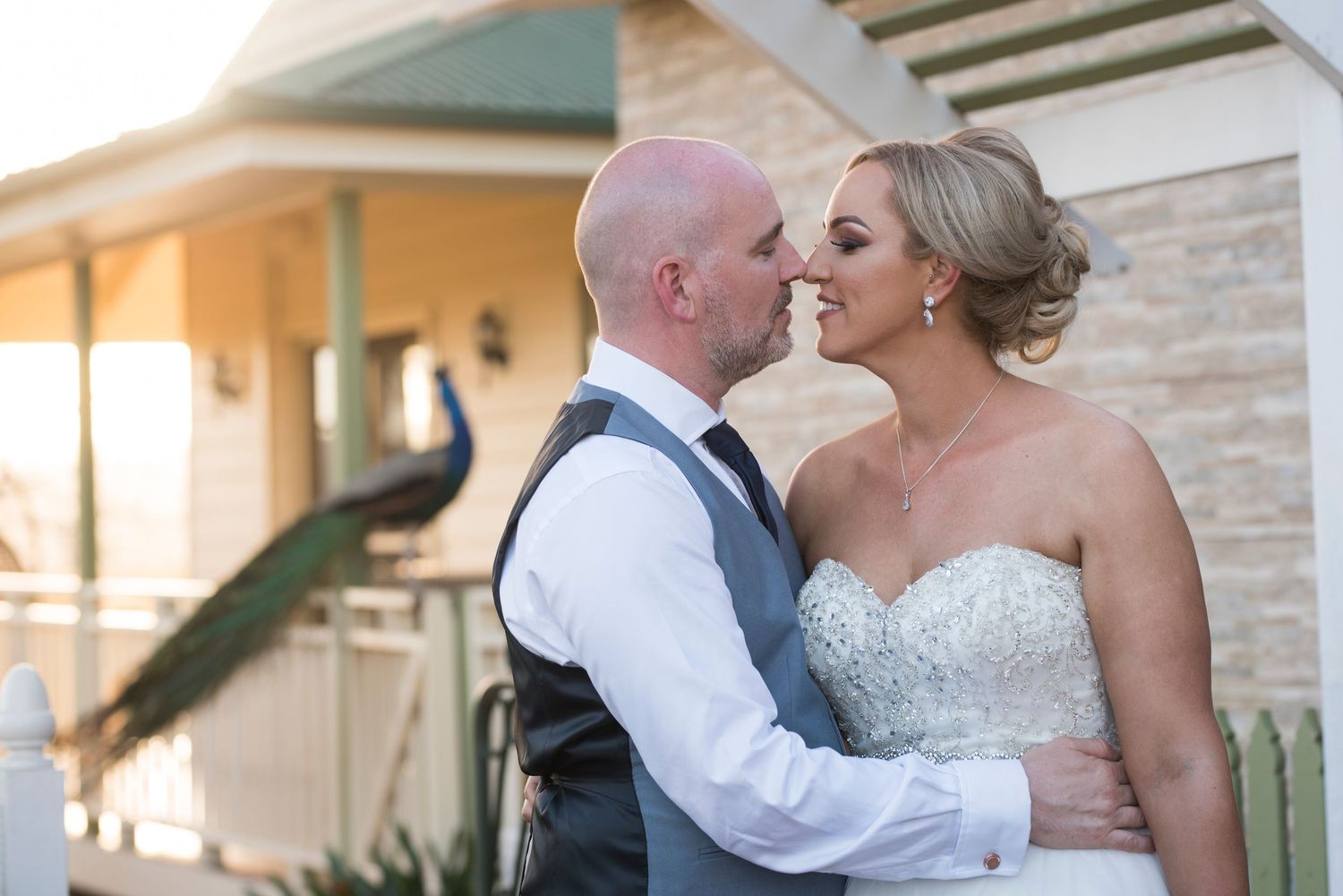 Bride and groom with peacock in background on wedding day.
