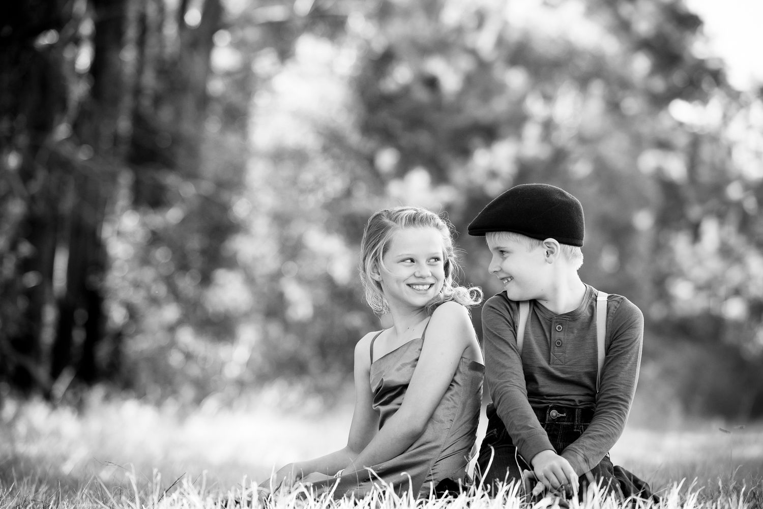 Black and white photo of children in grass during outdoor photoshoot.
