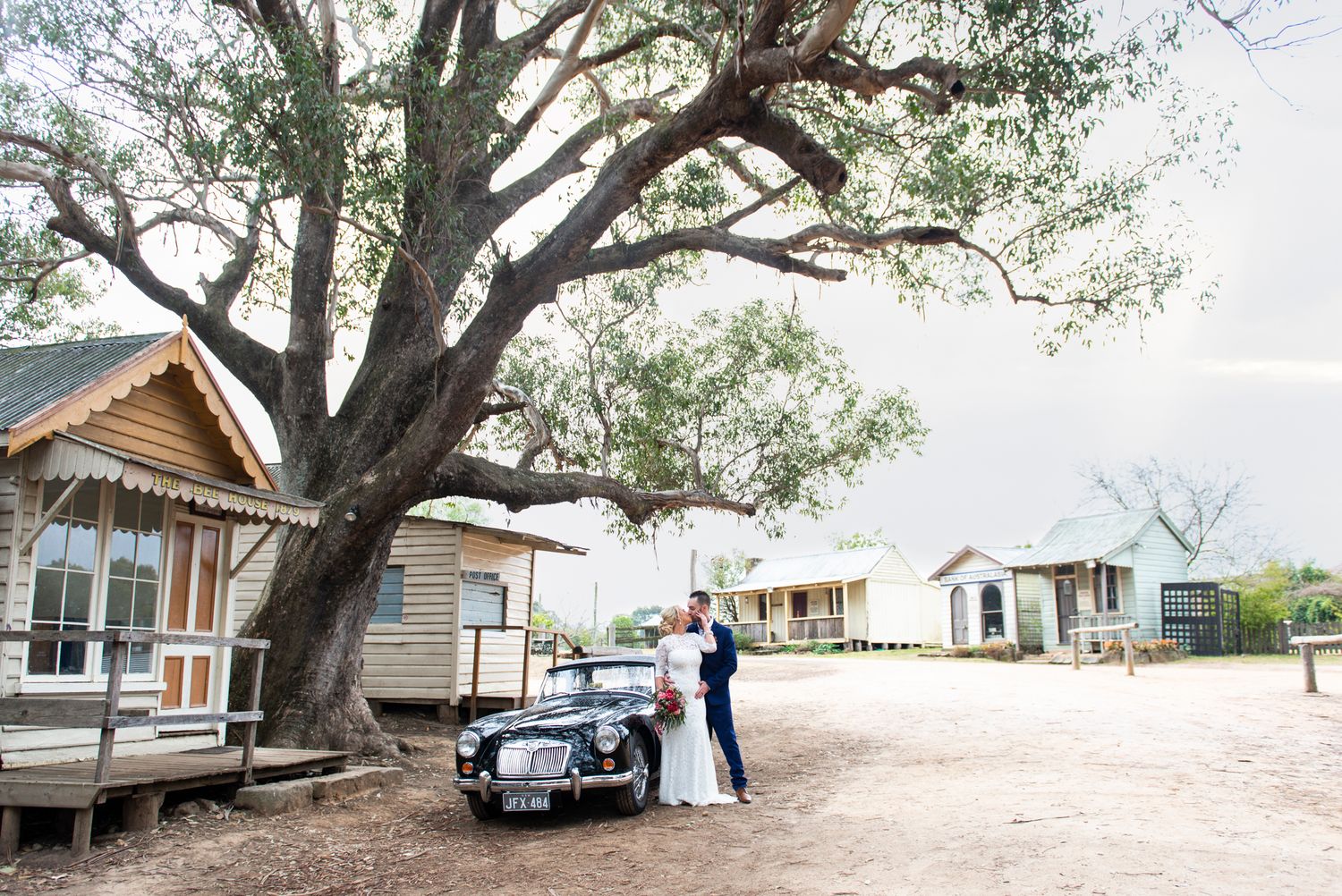 A row of rustic wooden cabins nestled under large oak trees at a rural retreat property.