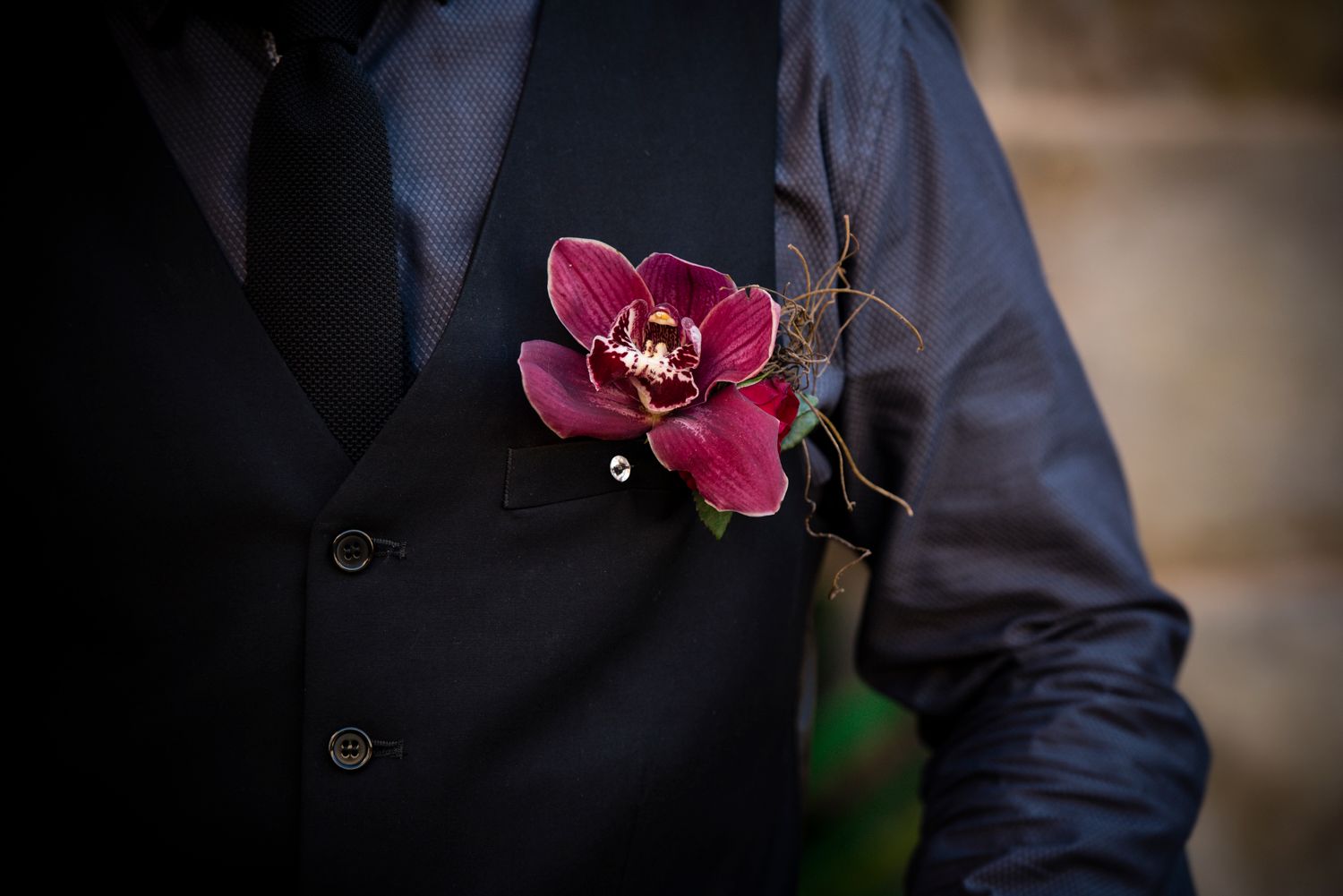 A groom in a dark suit with orchid boutonniere.