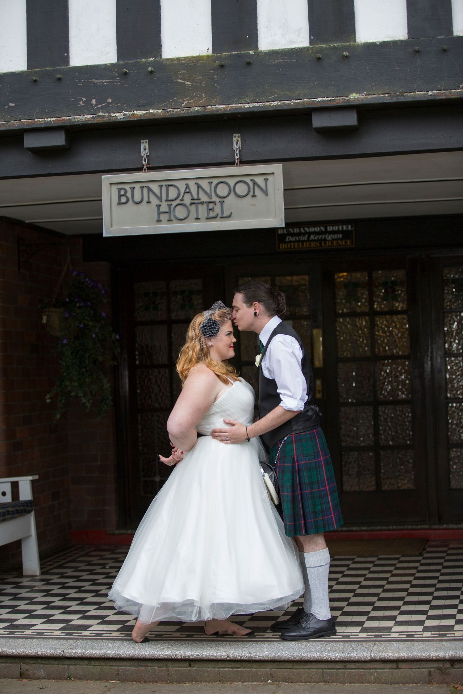 Wedding couple dancing and embracing outside historic Bundanoon building with checkered floor.