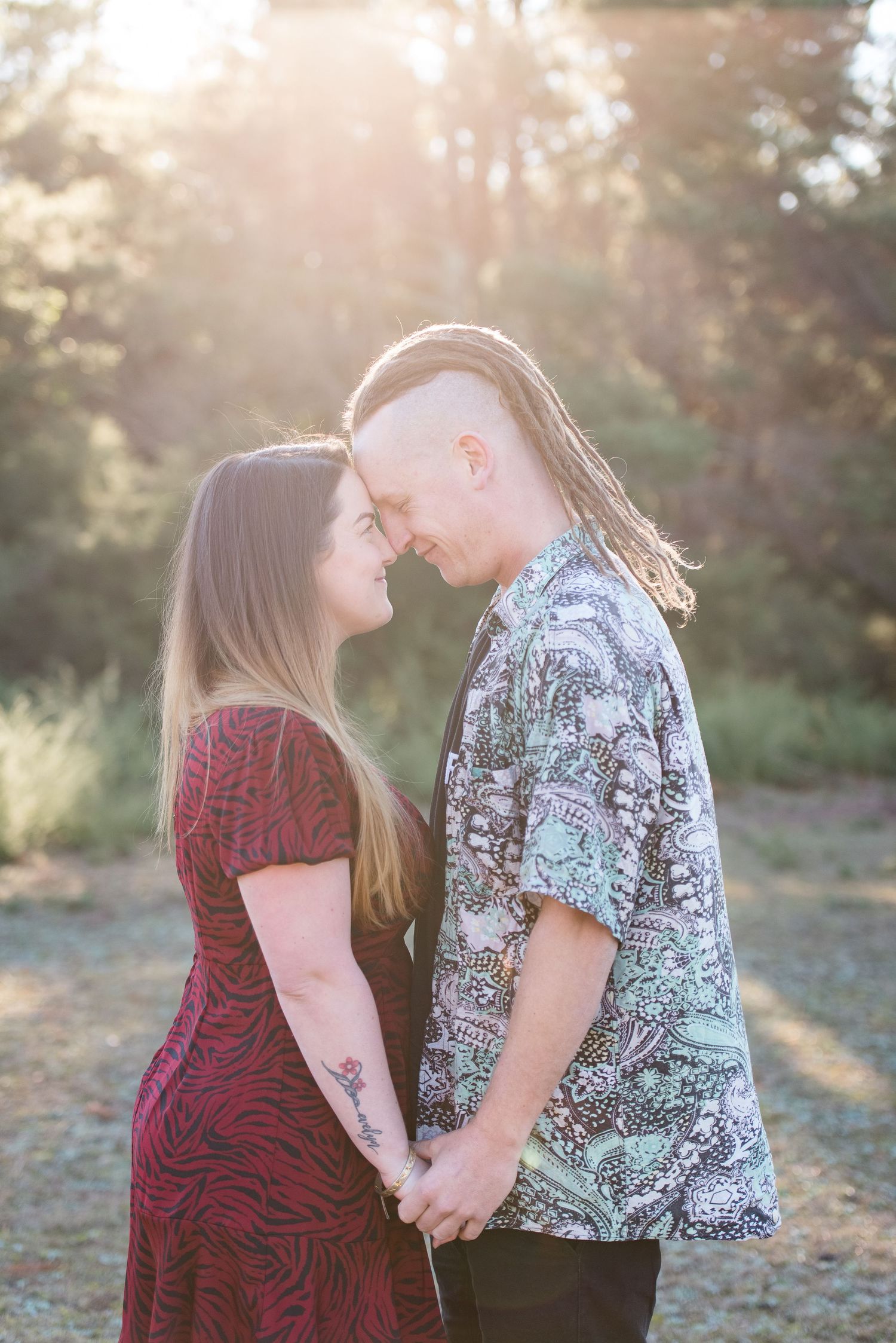 A couple in casual attire sharing romantic moments during golden hour outdoors.