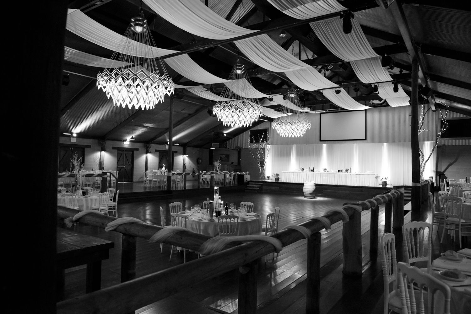 Modern industrial-style restaurant interior wedding venue with exposed ceiling ducts, pendant lights, and sleek dining furniture.