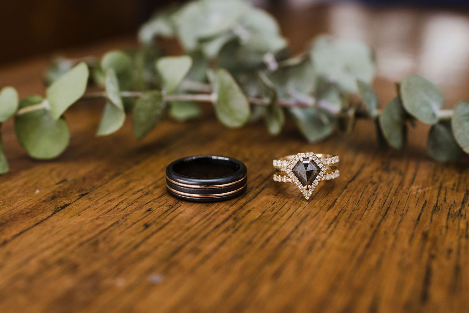 Wedding rings and floral details artistically arranged on rustic wooden surface.