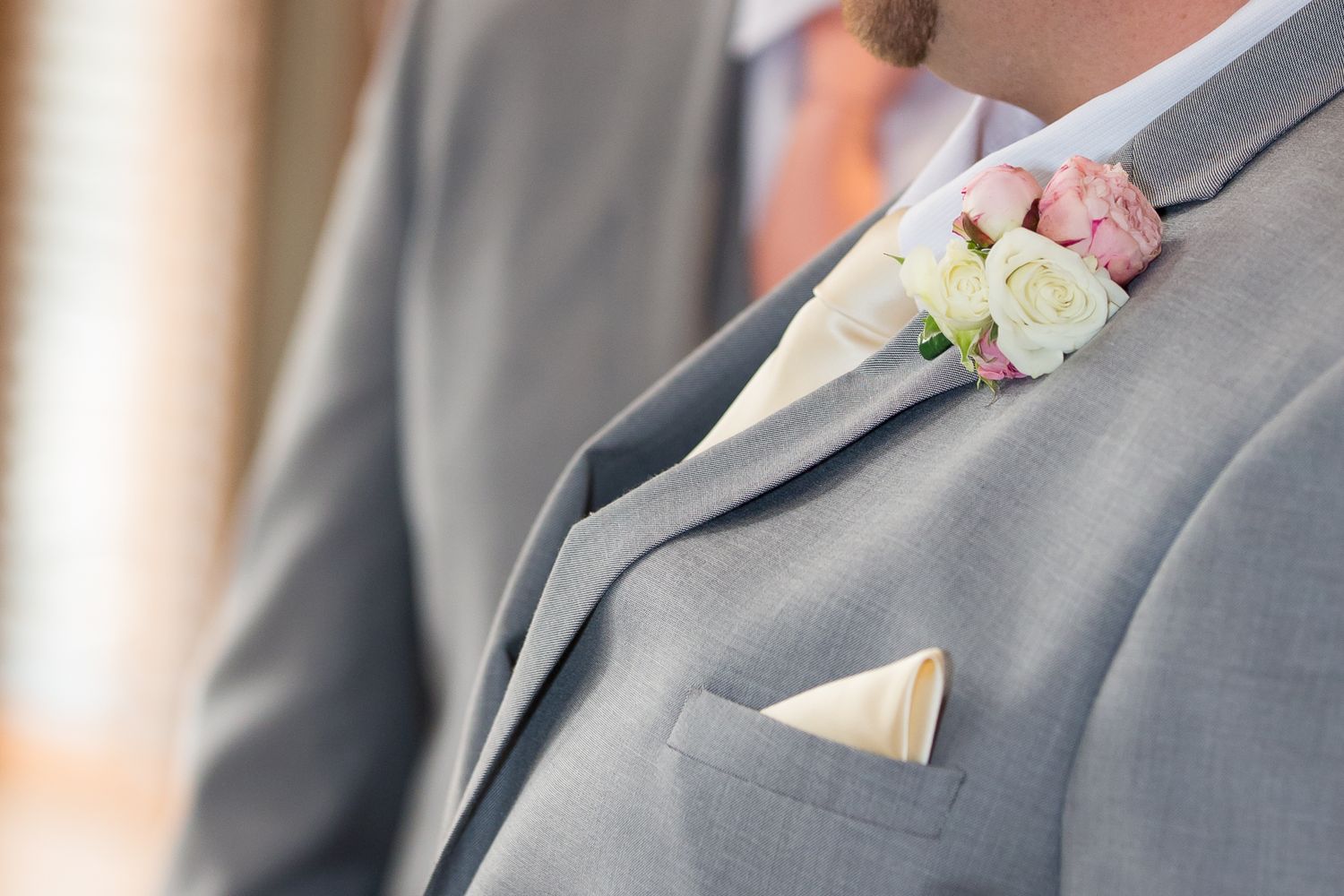 Groomsmen in matching gray suits with white boutonnieres stand in a row at a formal wedding ceremony.
