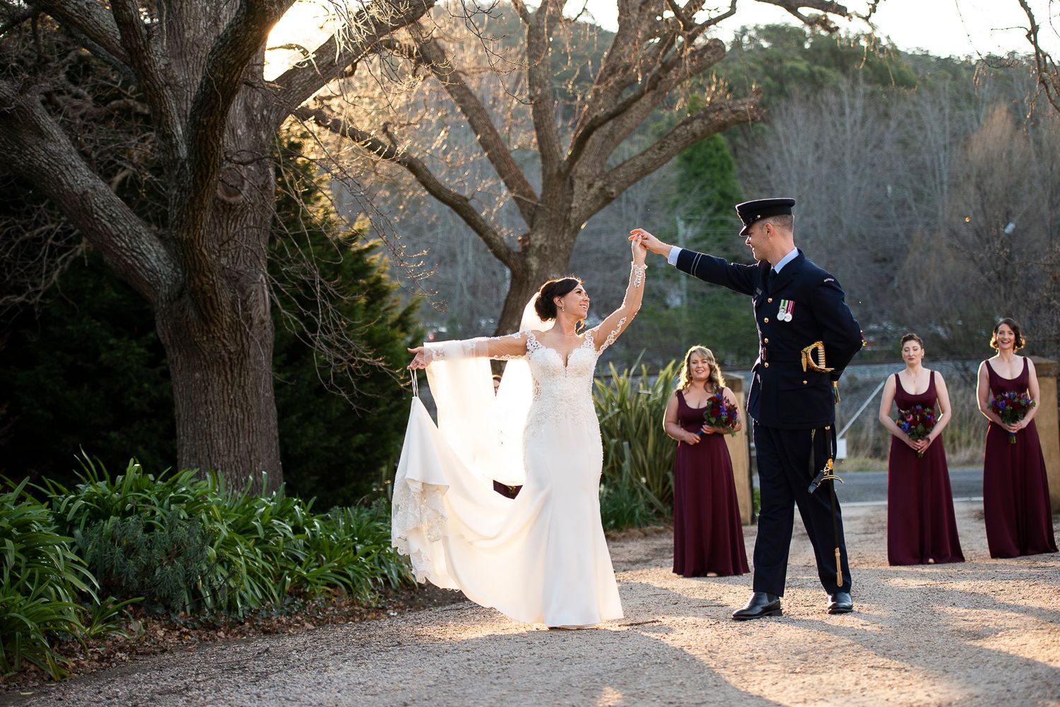 Wedding ceremony group poses beneath sprawling tree branches.