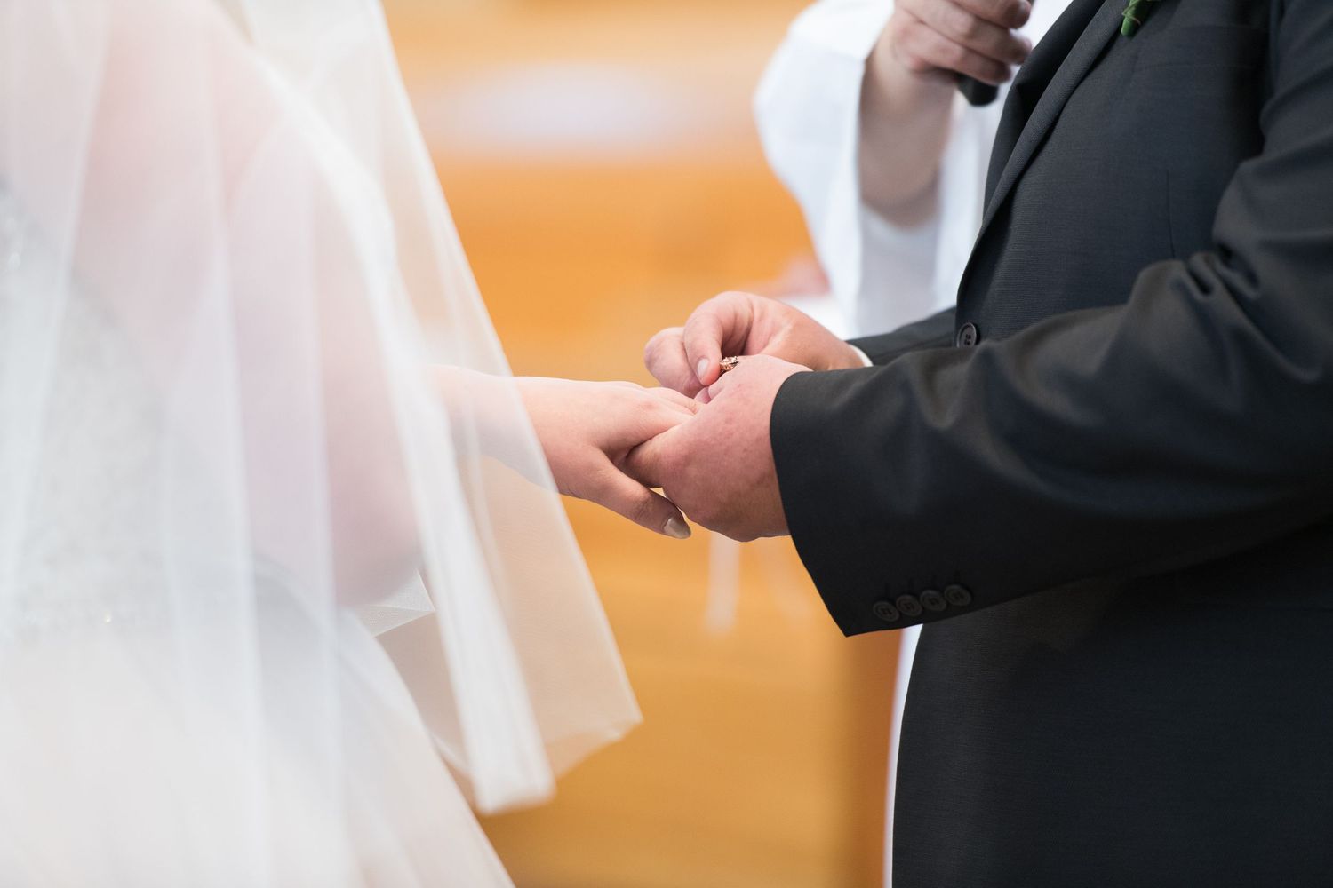 Close-up view of hands exchanging wedding rings during a traditional ceremony.