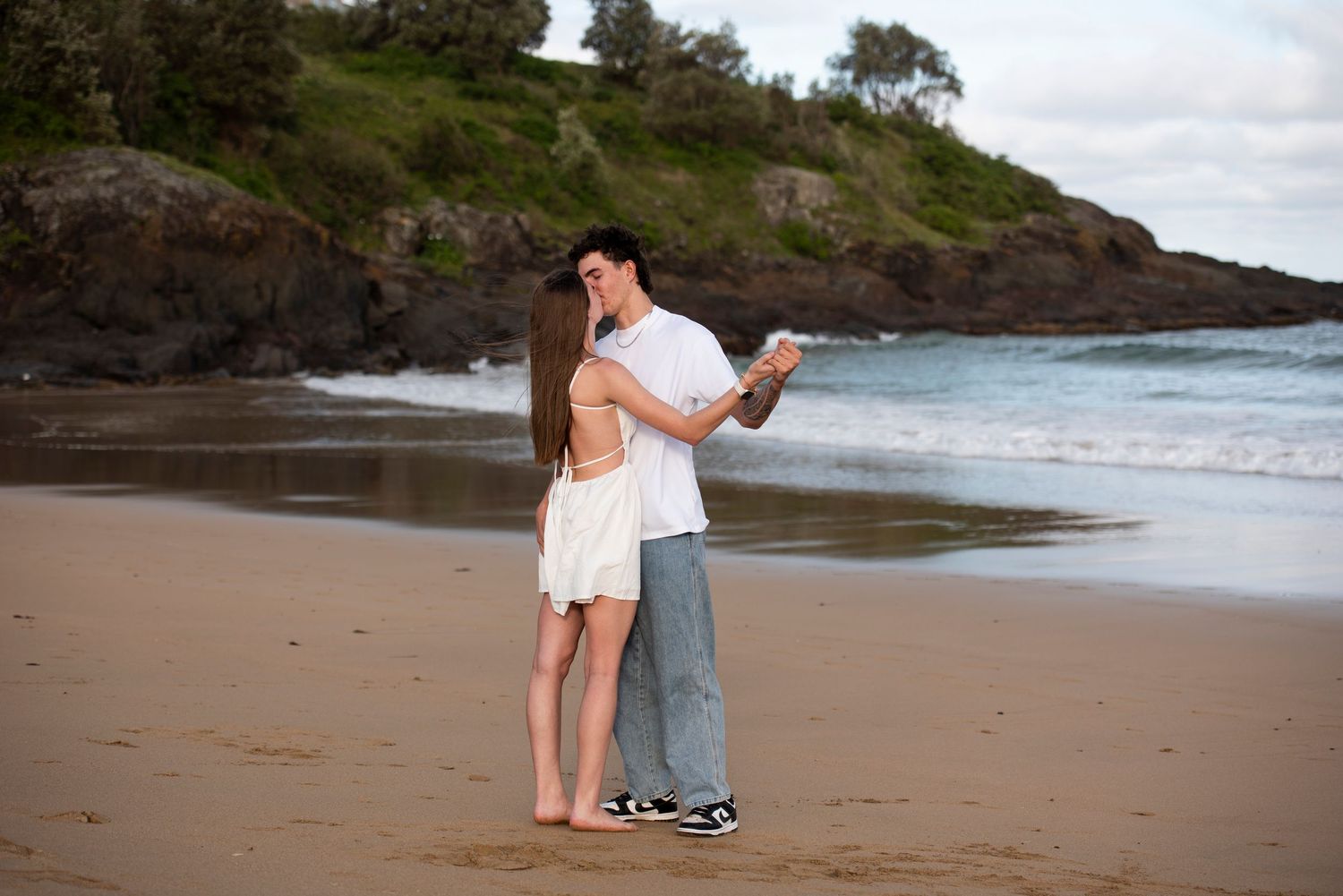 A couple dancing on a secluded beach in Kiama with rocky cliffs in the background.