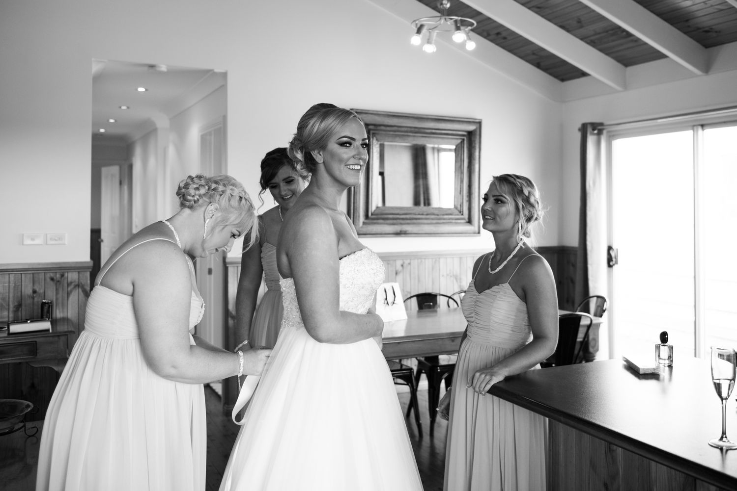 A series of black and white wedding preparation photos showing dress fitting and getting ready moments in a bridal suite.