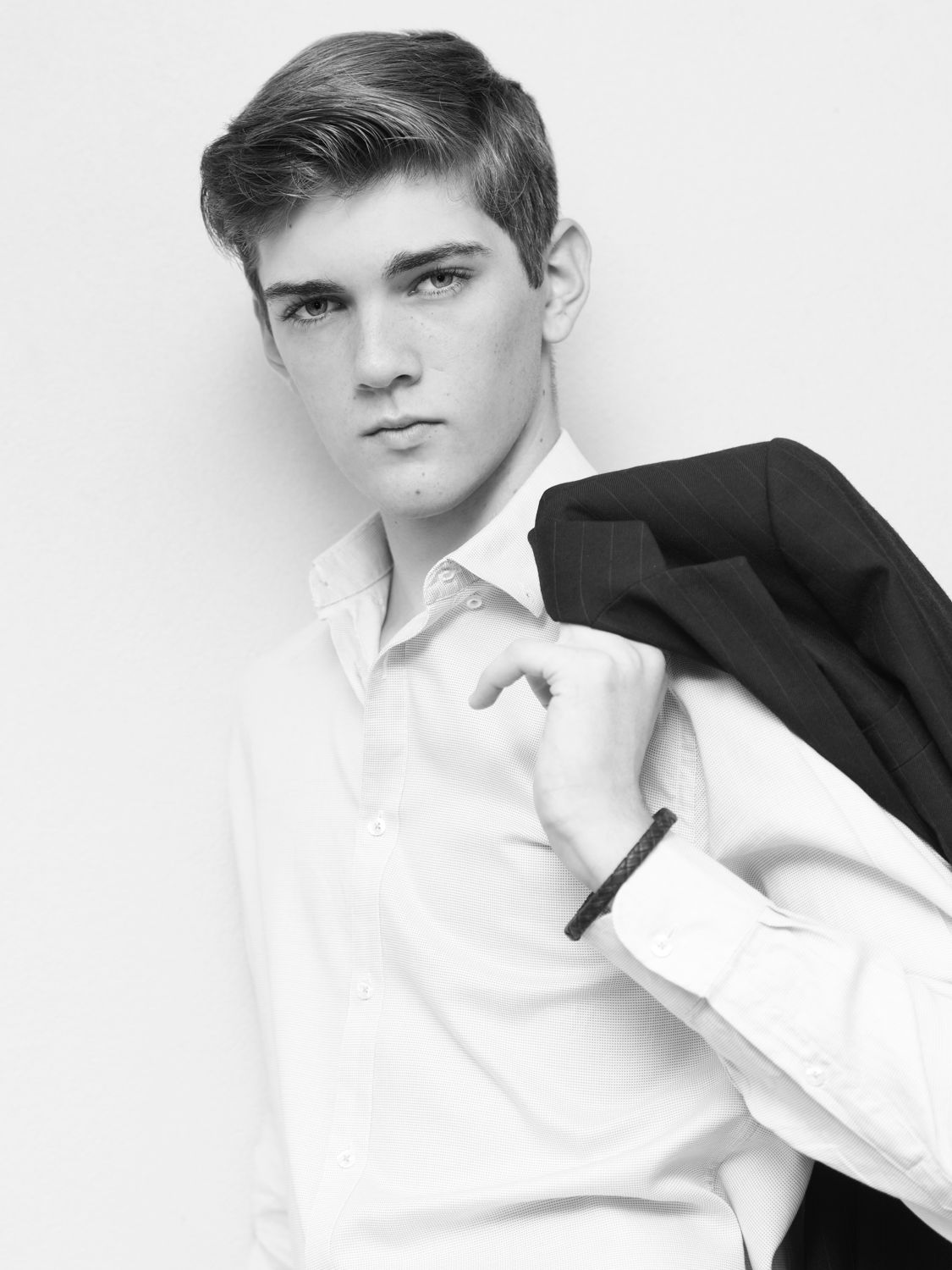 Black and white portrait of a young man in formal attire against a plain background.