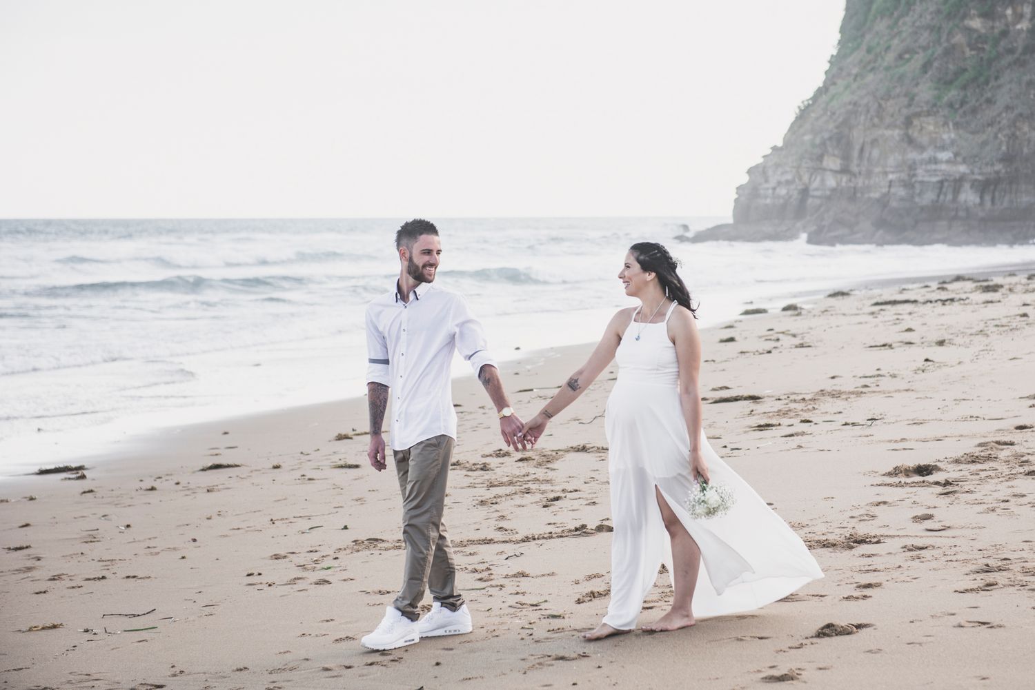Couple walking hand in hand along a scenic beach during sunset.