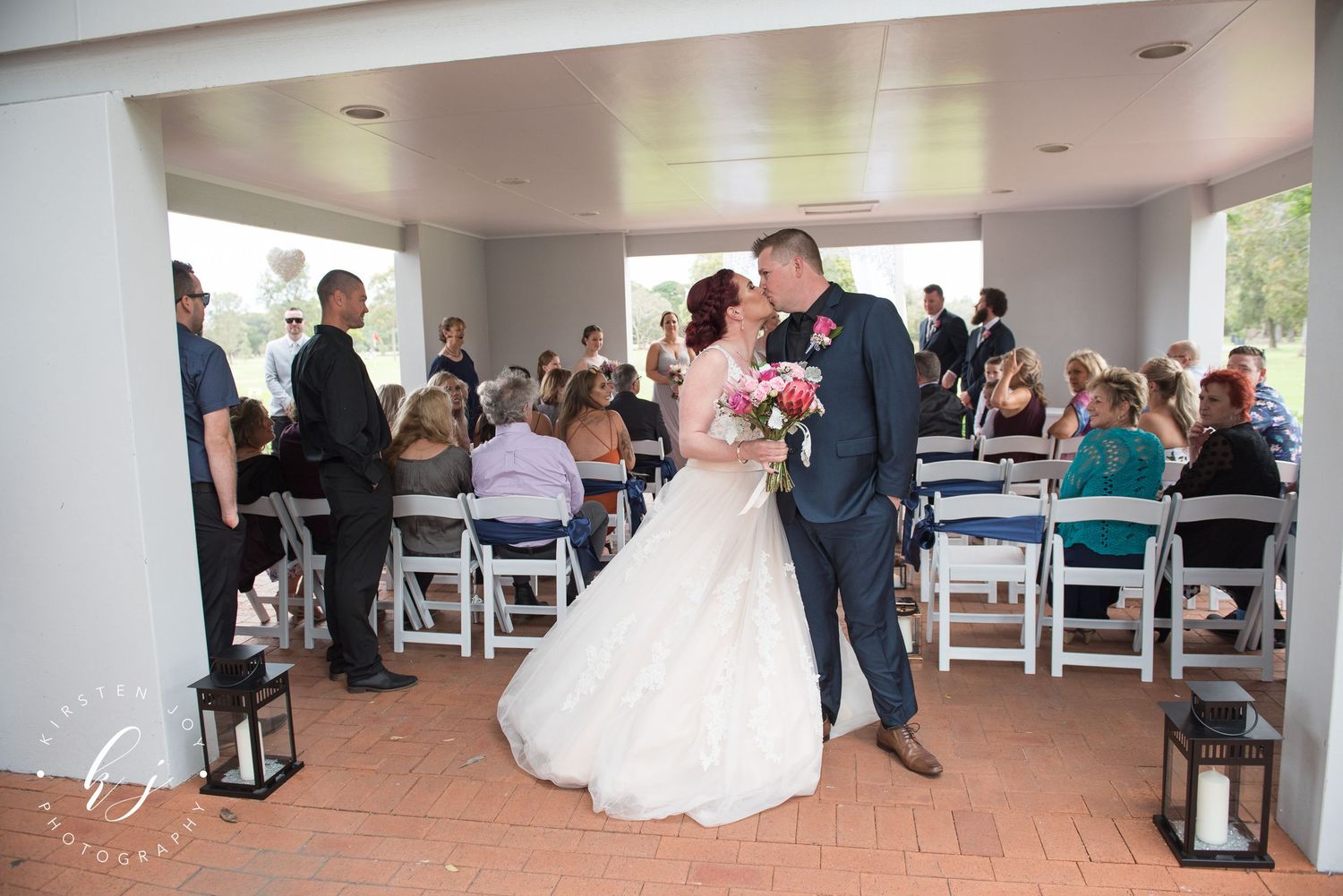 Indoor wedding venue with white chairs arranged in rows and decorative black lanterns along the aisle.