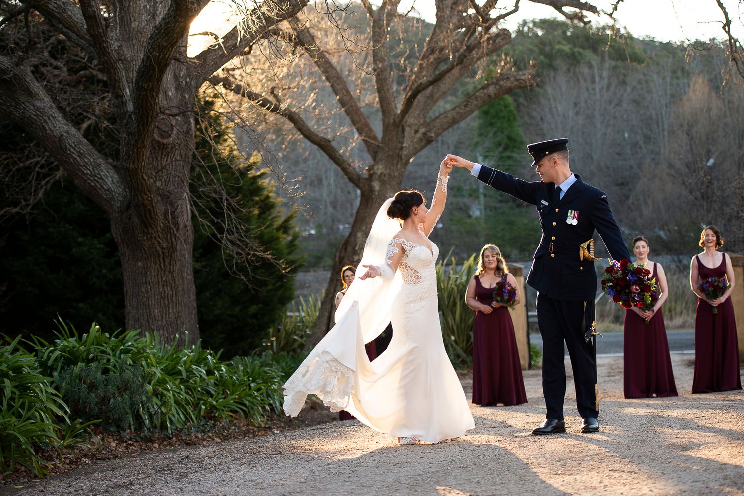 A wedding party poses together on a scenic outdoor path during golden hour lighting.