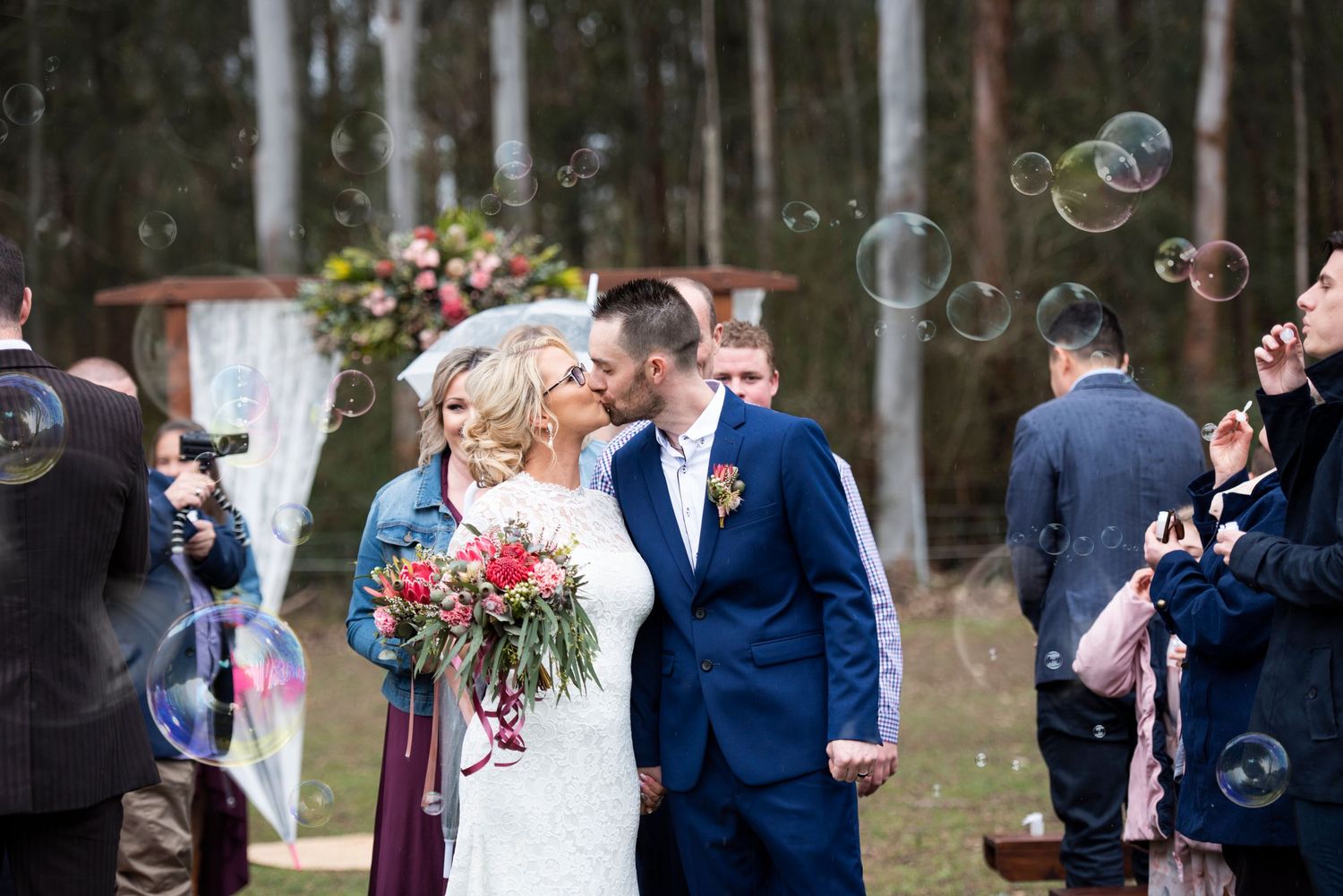 Wedding couple celebrates with guests as bubbles float through the air.