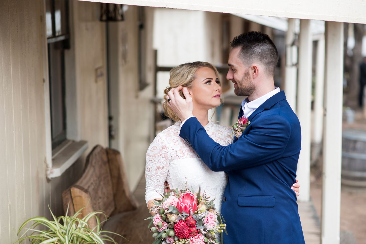 Bride and groom embraces on a front balcony and natural lighting.