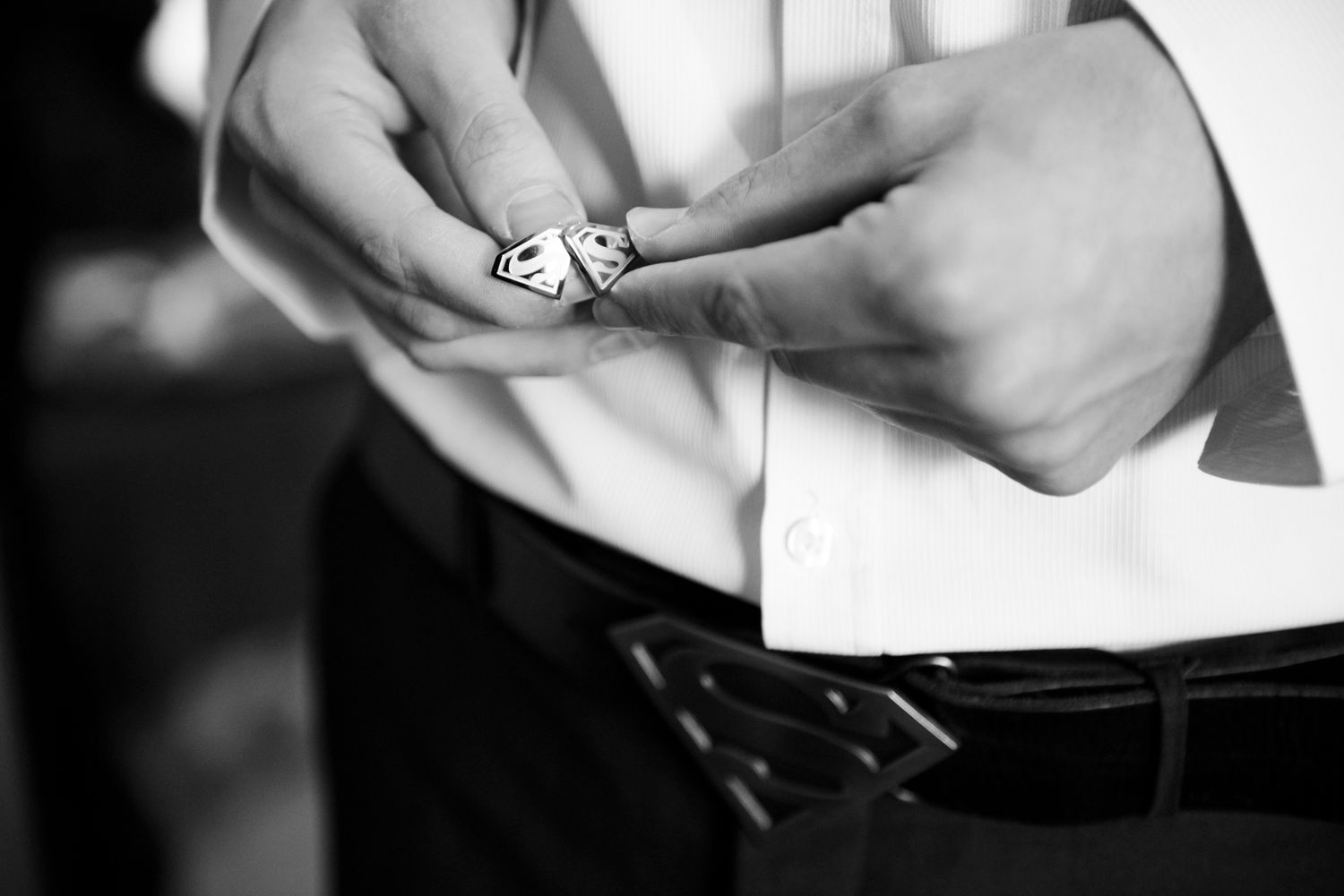 Close-up black and white photo of hands holding wedding rings.