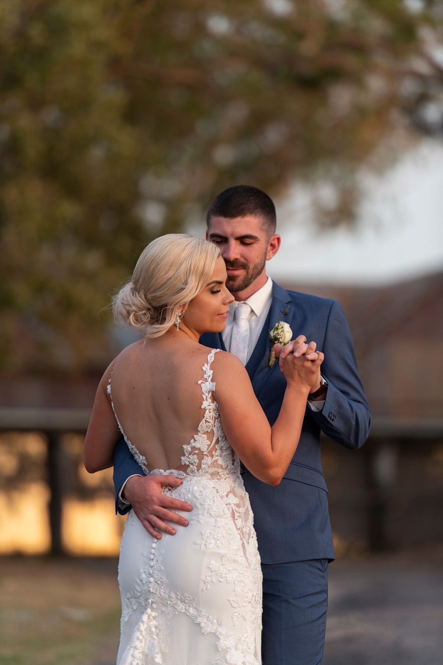 Romantic sunset portrait of a couple in wedding attire sharing an intimate dance moment.