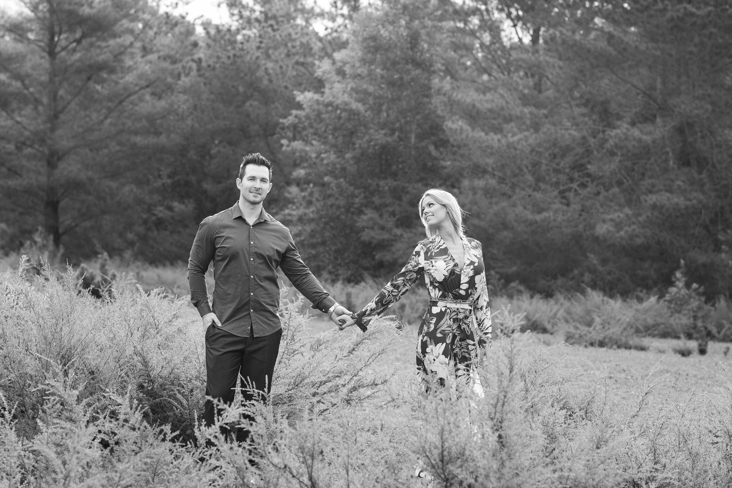 Black and white romantic couple portraits in a rustic outdoor setting with pine trees.