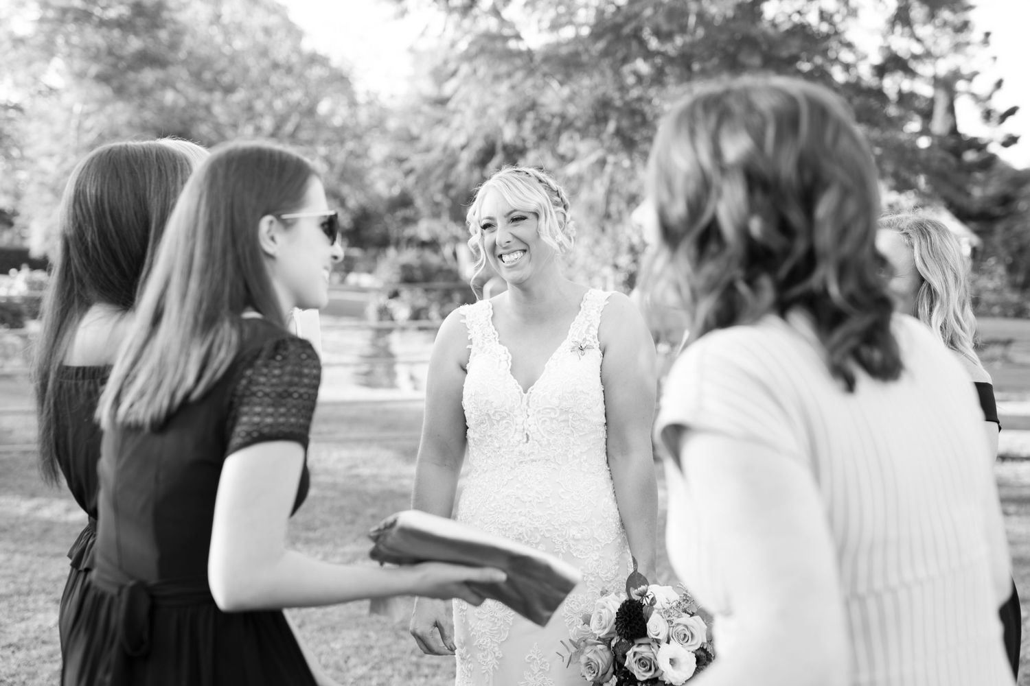 A series of black and white wedding photos showing candid moments between bride and guests during an outdoor celebration.