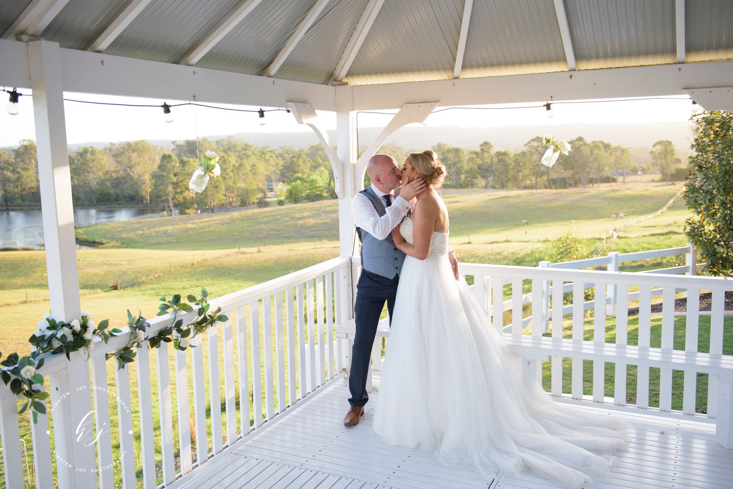 A romantic moment on a white gazebo overlooking a scenic lake and landscape.