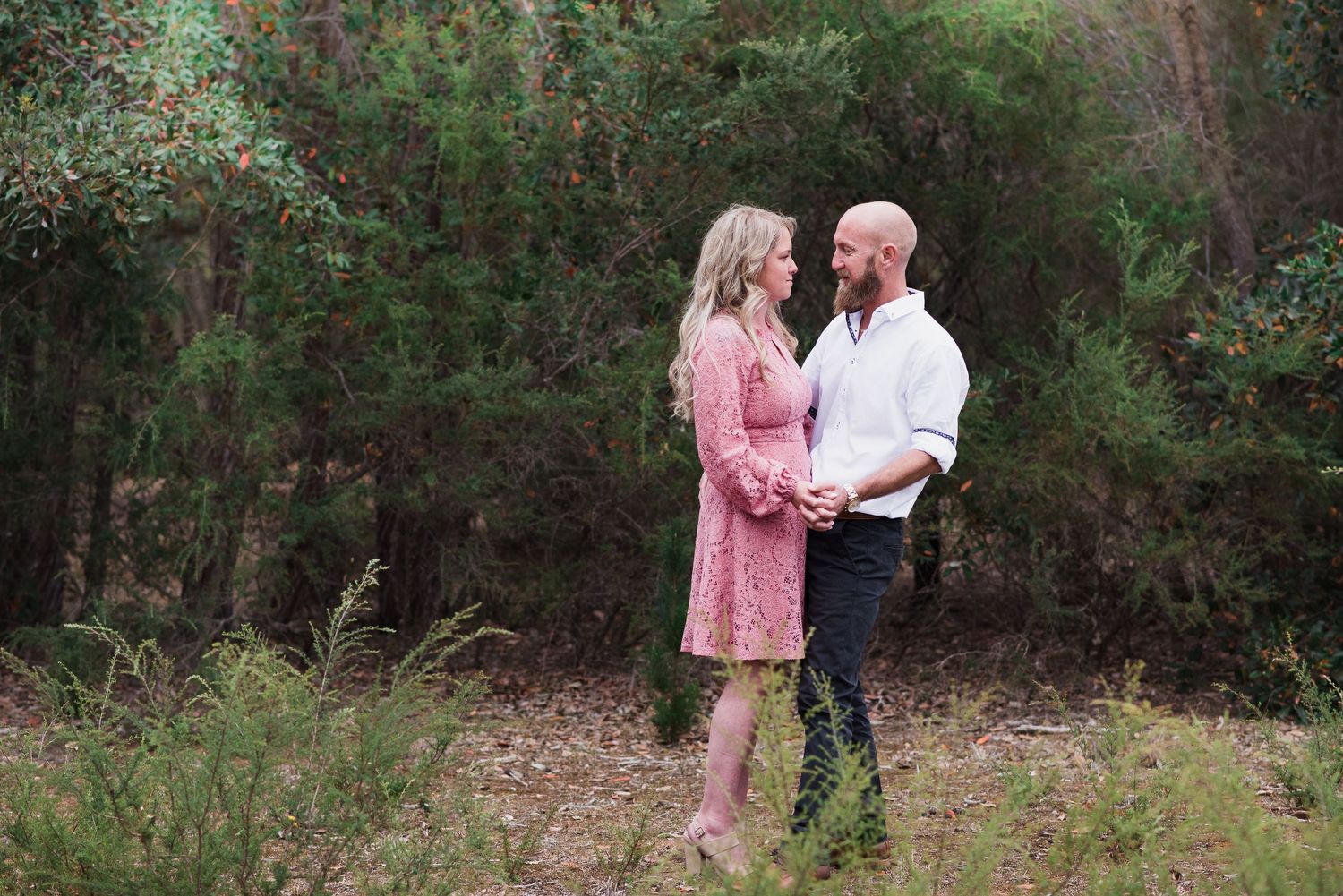 A couple sharing intimate moments in a natural garden setting with green foliage.