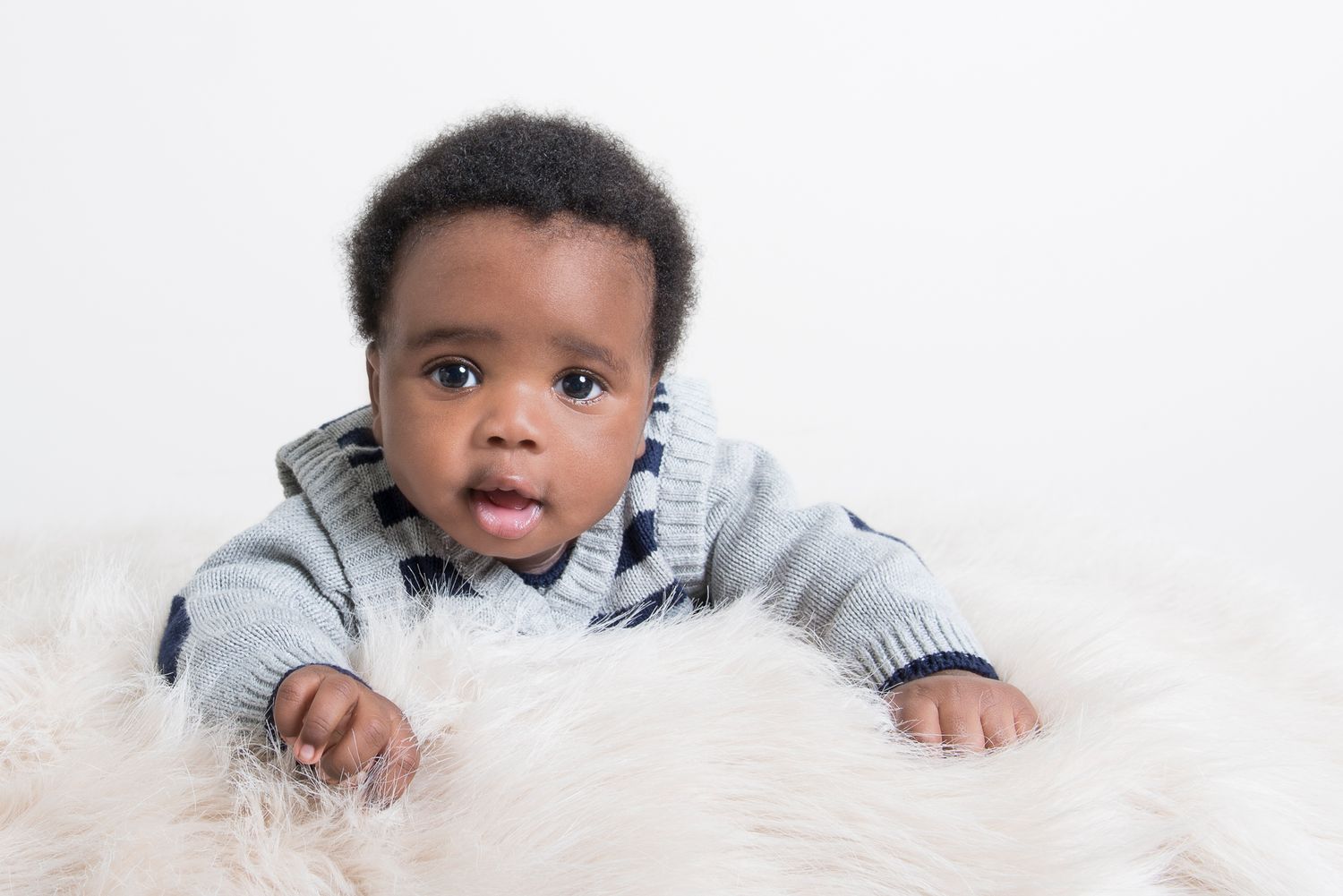 Baby lying on soft white blanket during a professional photo session.