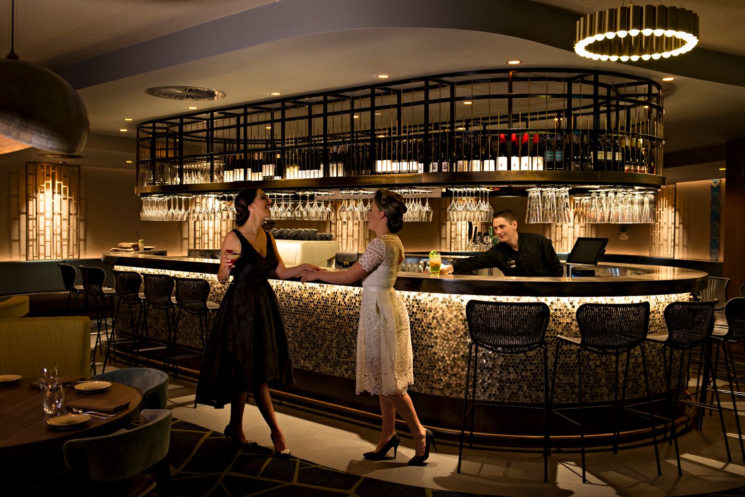 Modern restaurant interior with circular pendant lighting and sleek bar area.