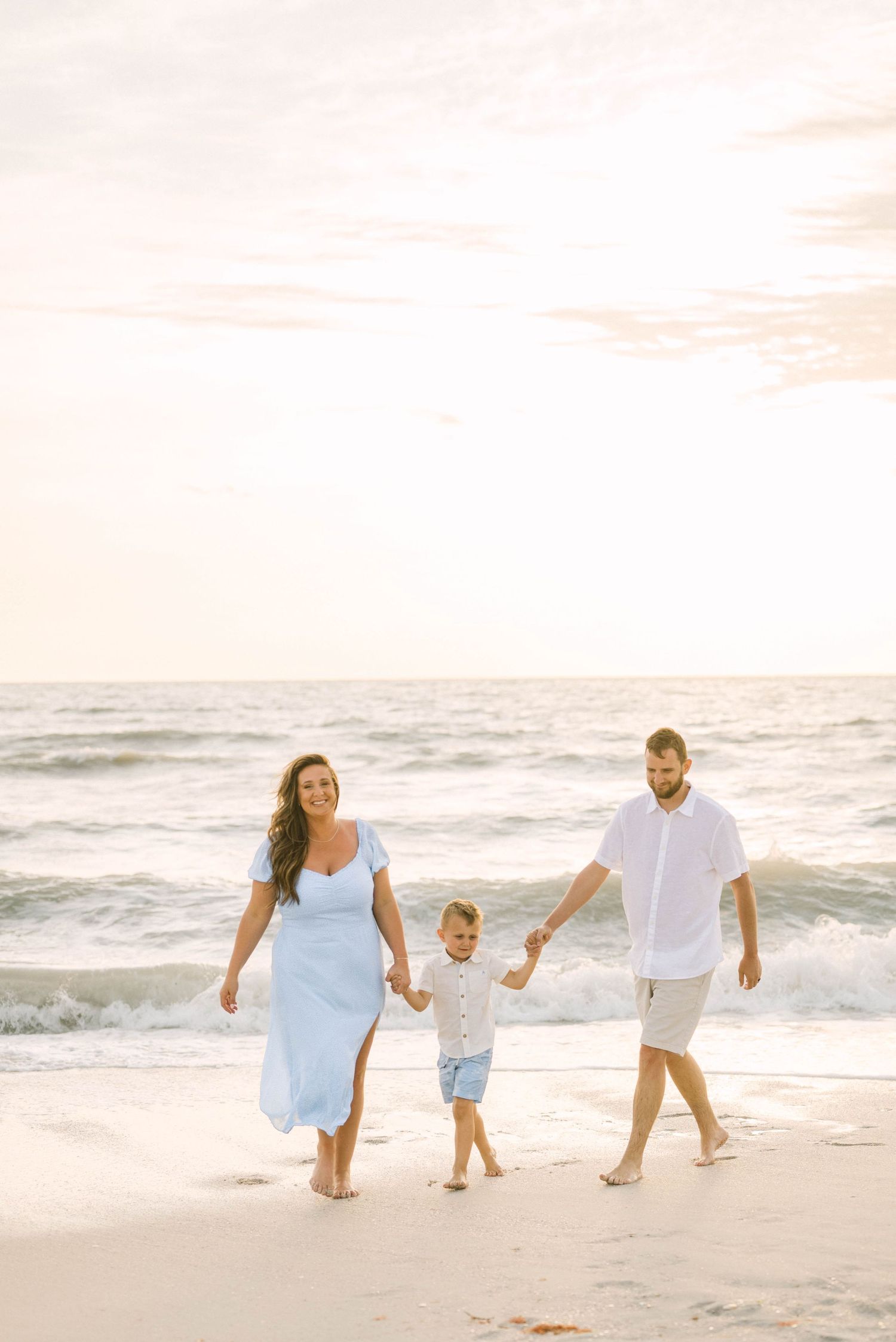 Lifestyle family portrait at Barefoot Beach with soft golden light.