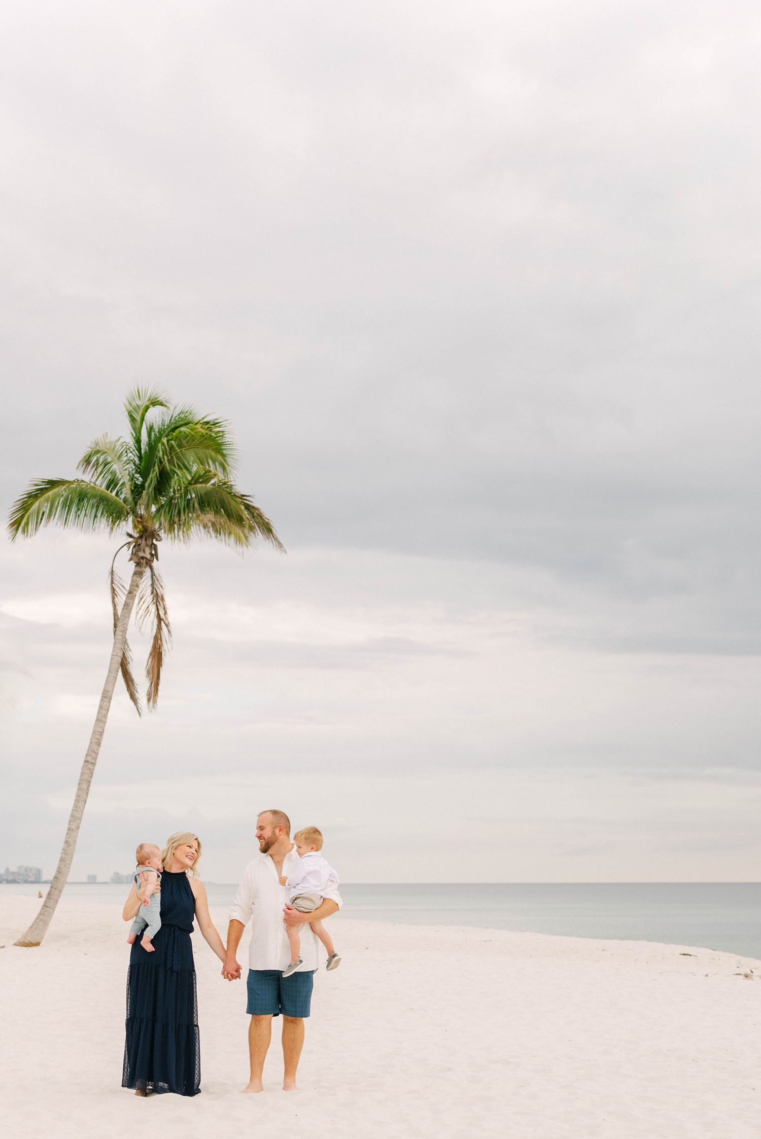 Lifestyle family portrait at Barefoot Beach with soft golden light.