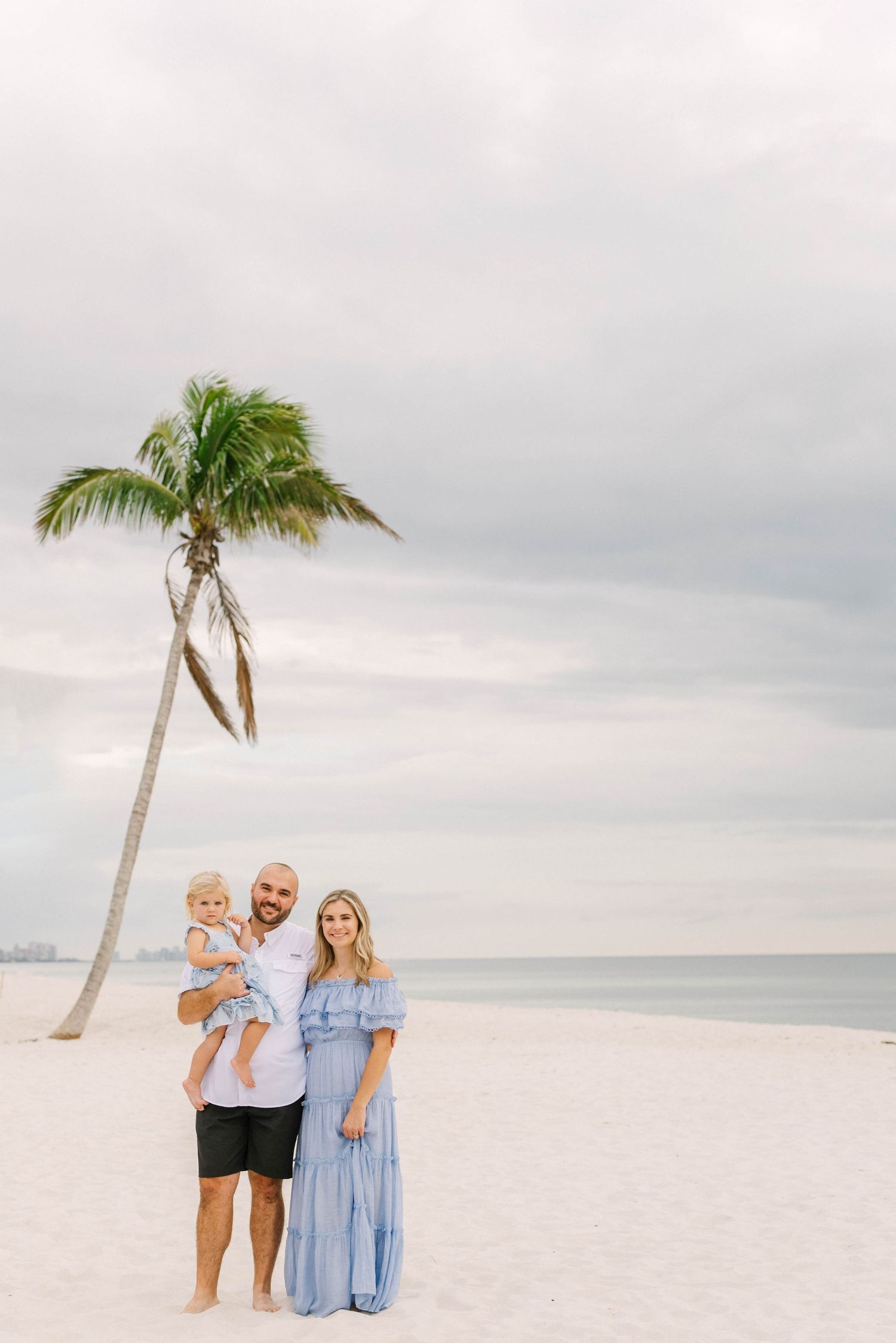 Lifestyle family portrait at Barefoot Beach with soft golden light.