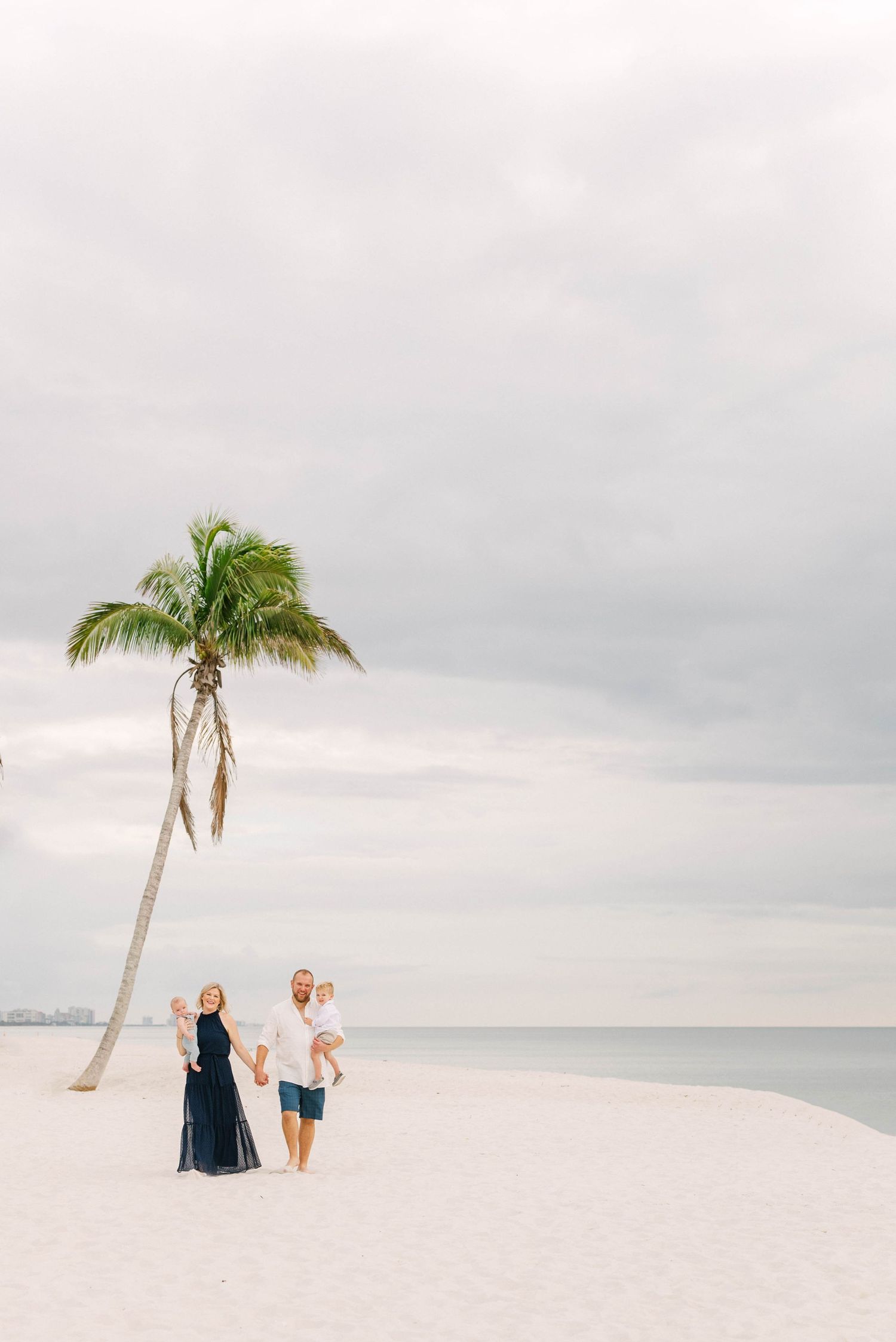 Lifestyle family portrait at Barefoot Beach with soft golden light.