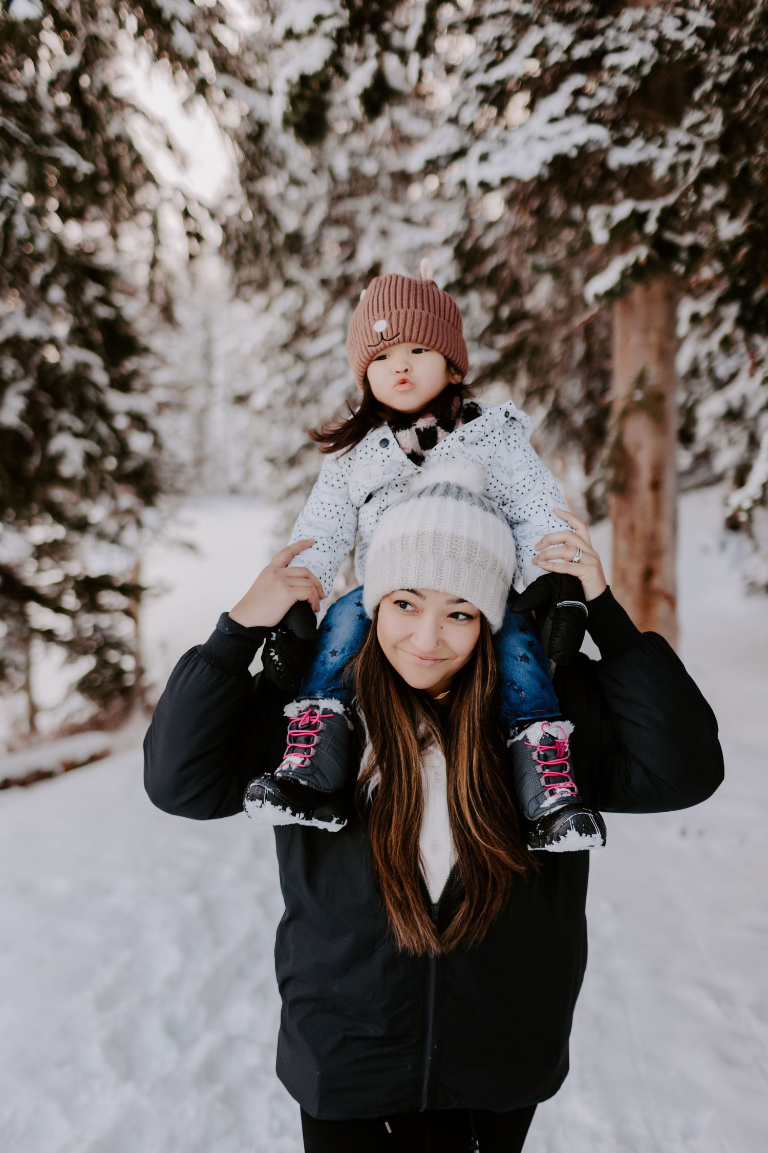 Rebecca Glass Photography carrying her daughter on her shoulders during a family session in a snowy forest.