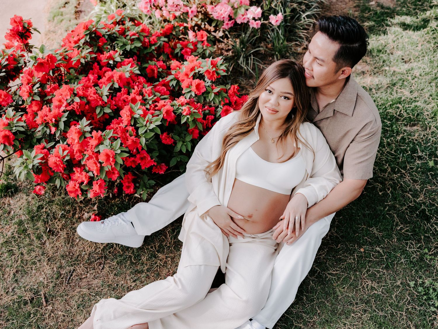 Pregnant couple posing next to flowers while doing a maternity photography session with Rebecca Glass Photography in OKC.