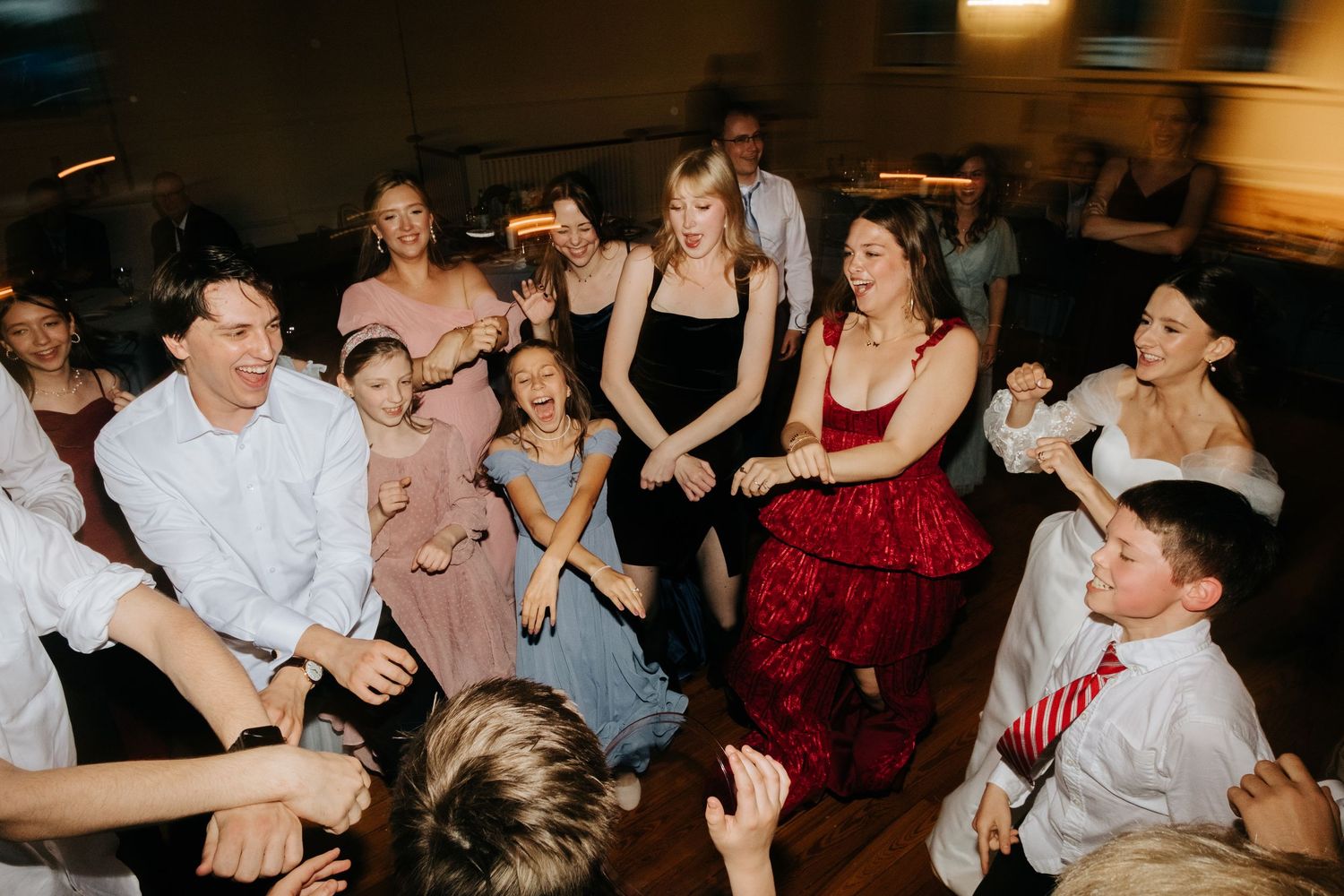 Wedding guests dancing and celebrating together on the dance floor during reception.