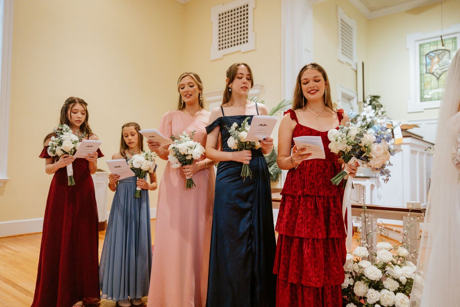 A collage of wedding party photos showing bridesmaids in burgundy and dusty blue dresses posing together.