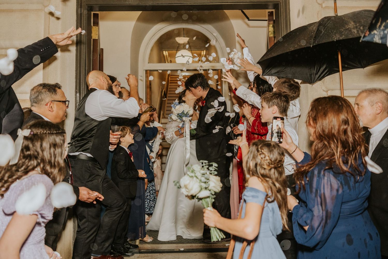 Newlywed couple exits church as guests shower them with confetti in joyous wedding celebration.