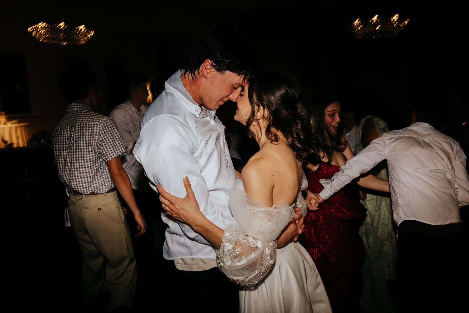 Couples dancing together in a dimly lit reception venue with romantic ambient lighting.