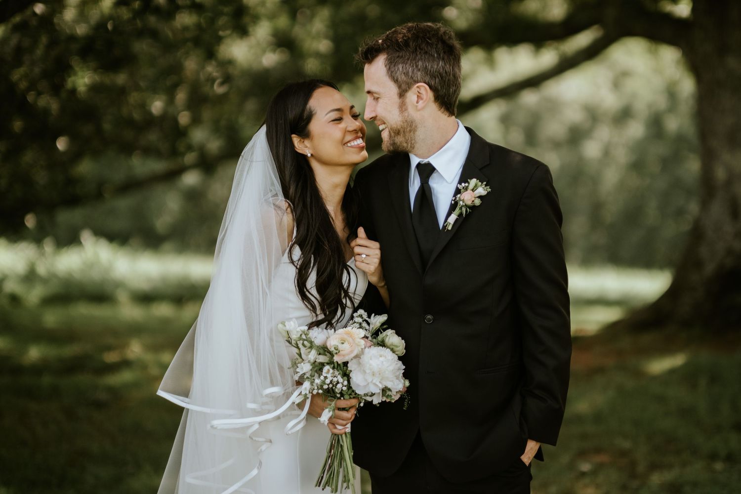 A bride and groom share intimate moments in a romantic outdoor garden setting during their wedding photoshoot.