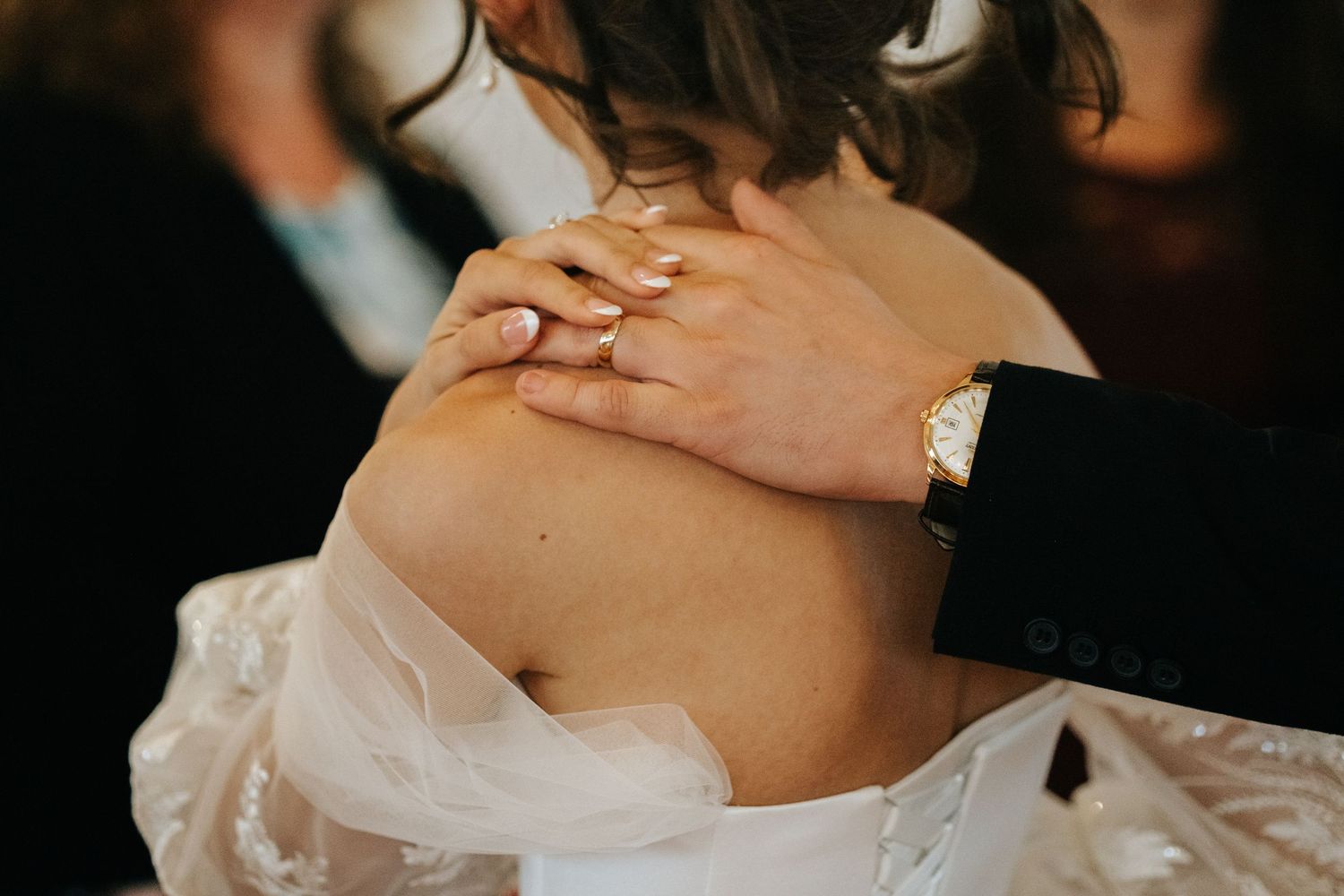 Close-up detail of a white lace wedding dress against dark background.