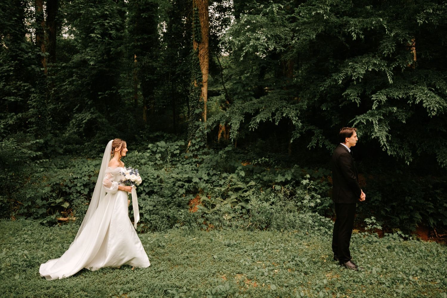 A couple having their first look moment in a lush forest setting at their wedding.