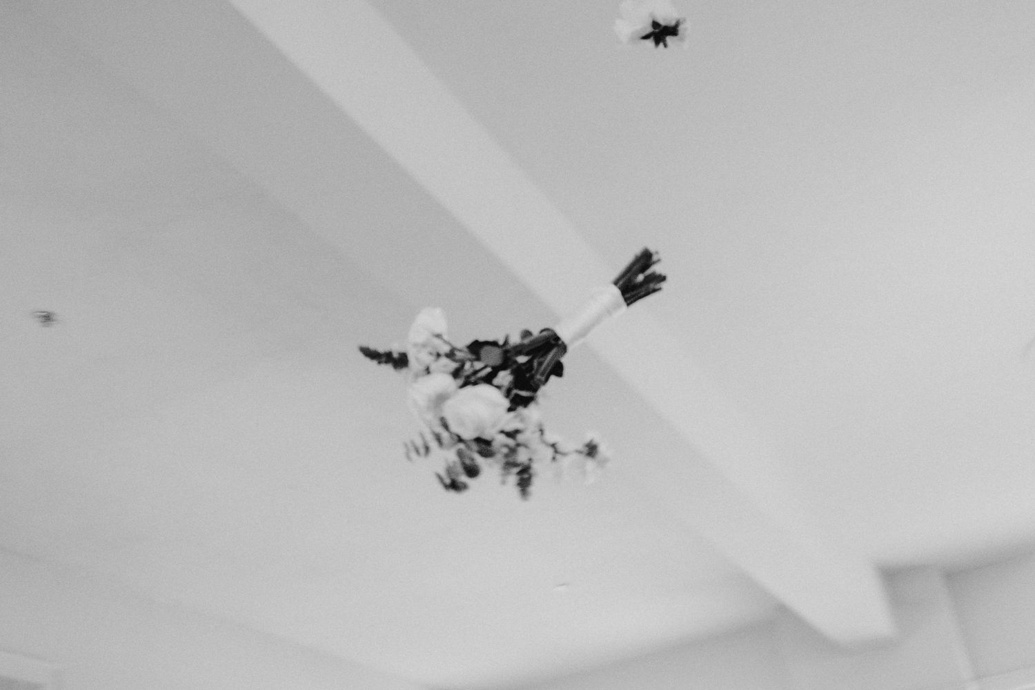Black and white aerial view of confetti scattered across a minimalist white ceiling.