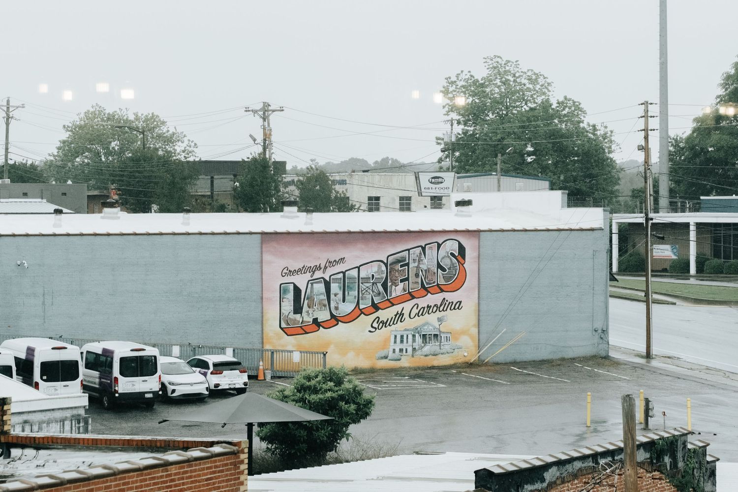 Industrial buildings and vehicles line a street with graffiti visible on walls in an urban setting.