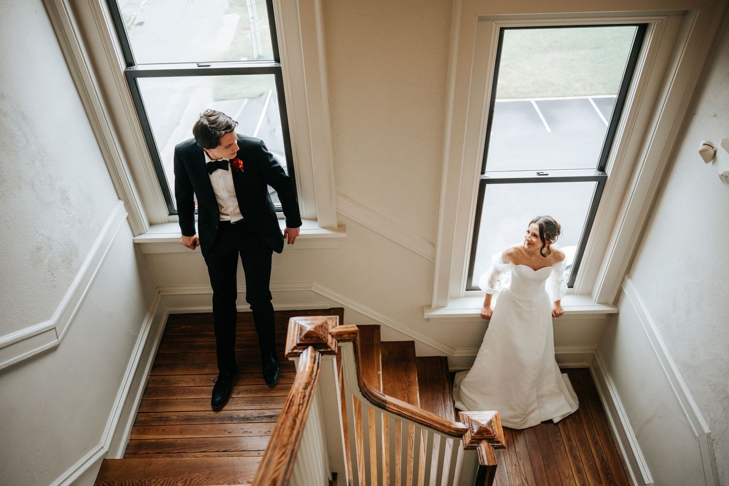 An artistic overhead shot of a couple walking down vintage wooden stairs in wedding attire.