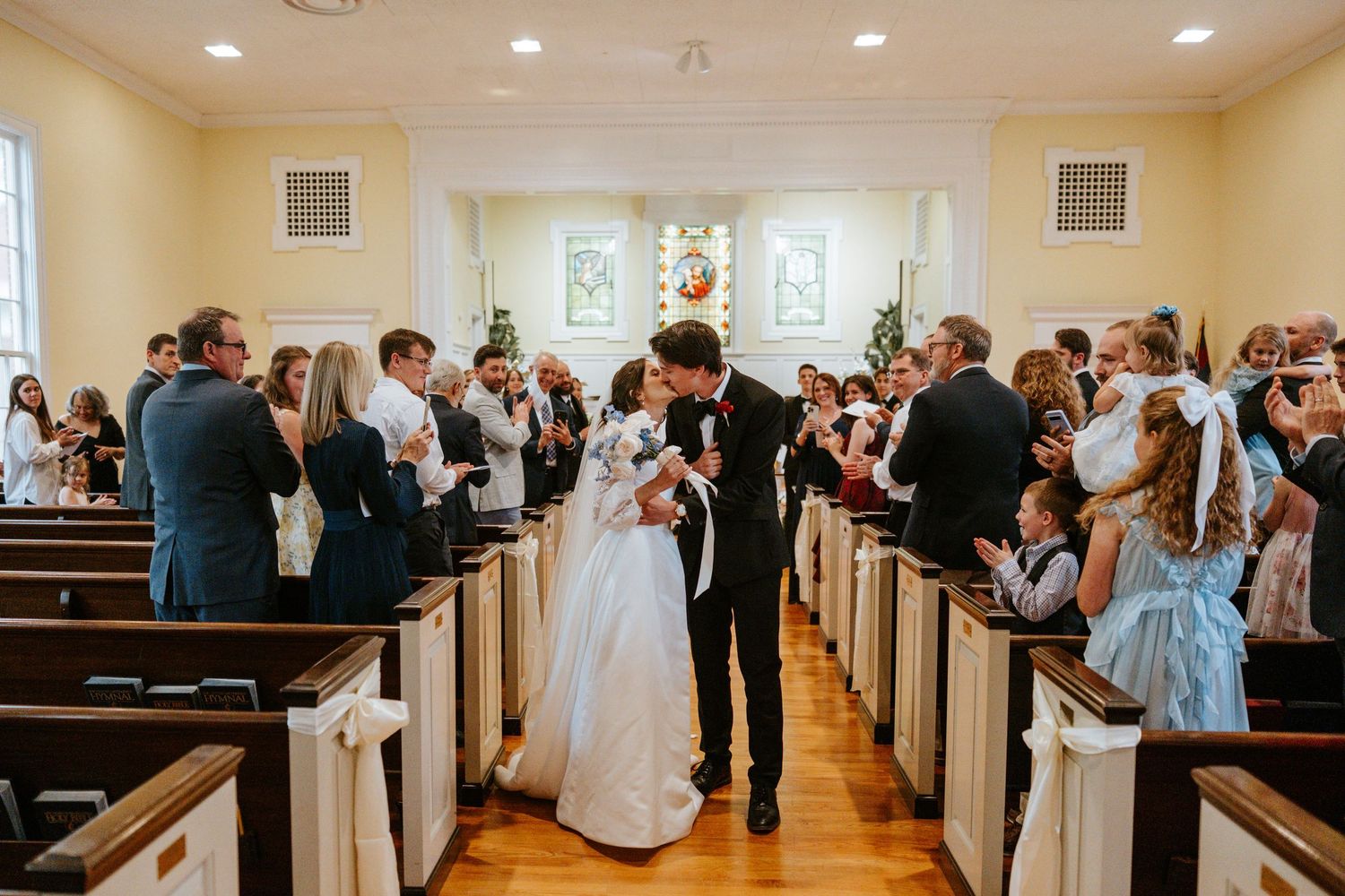 A panoramic collage of wedding ceremony moments inside a bright church with wooden pews and stained glass windows.