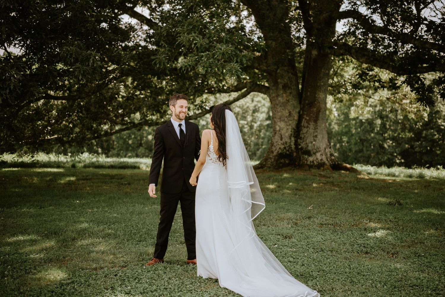 A romantic wedding couple poses together in a lush garden setting during their outdoor celebration.