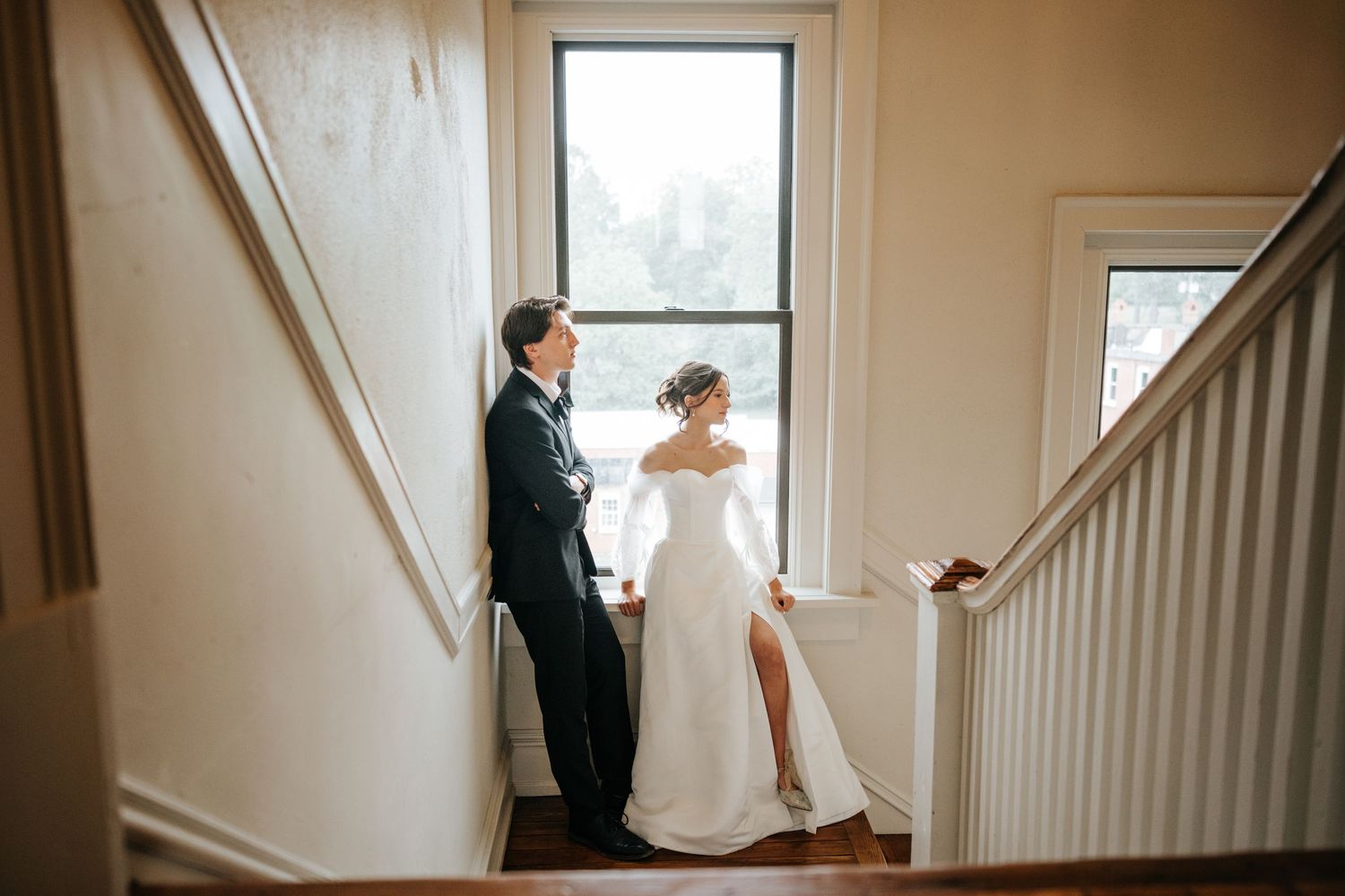 Elegant interior staircase with white walls and natural light streaming through windows.