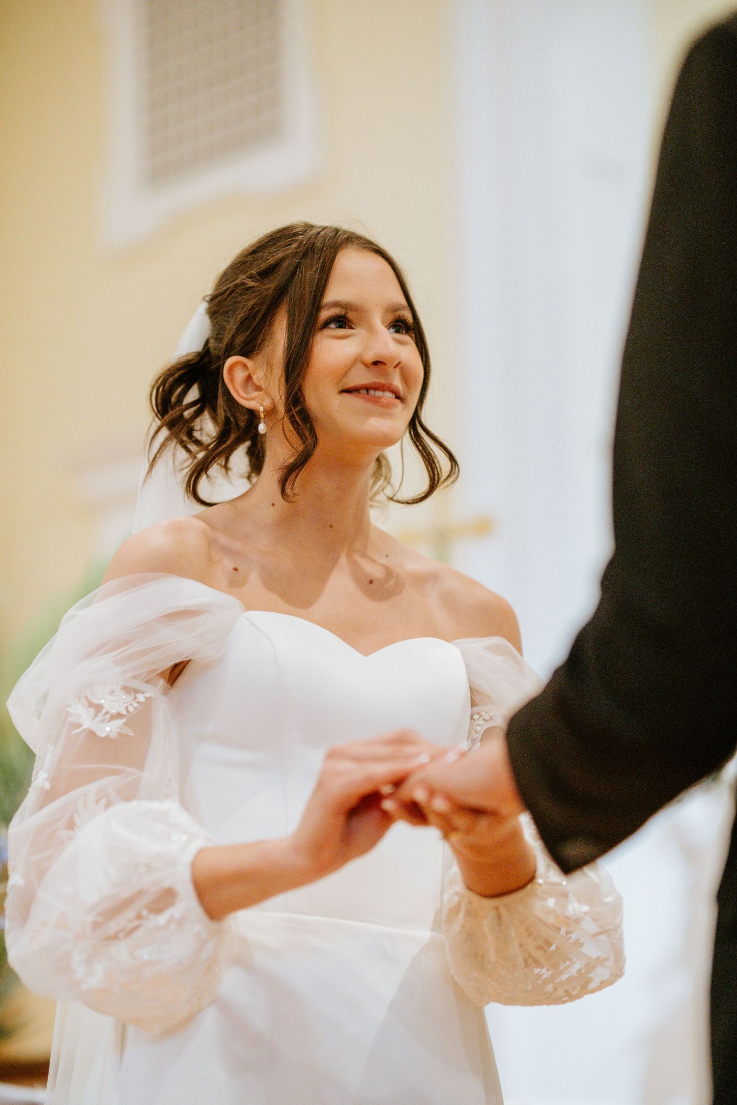 A bride in a white wedding dress dances joyfully in a bright indoor setting.